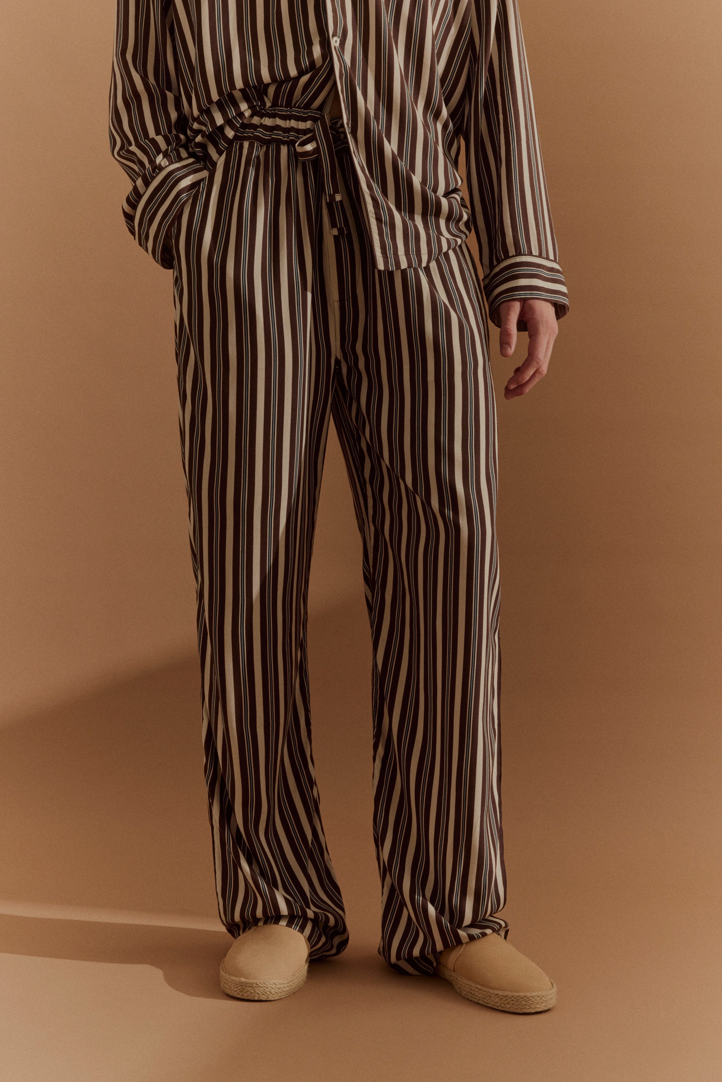 Gestreifter Pyjama-Set in Braun und Beige, Modelbild, entspannte Haltung.