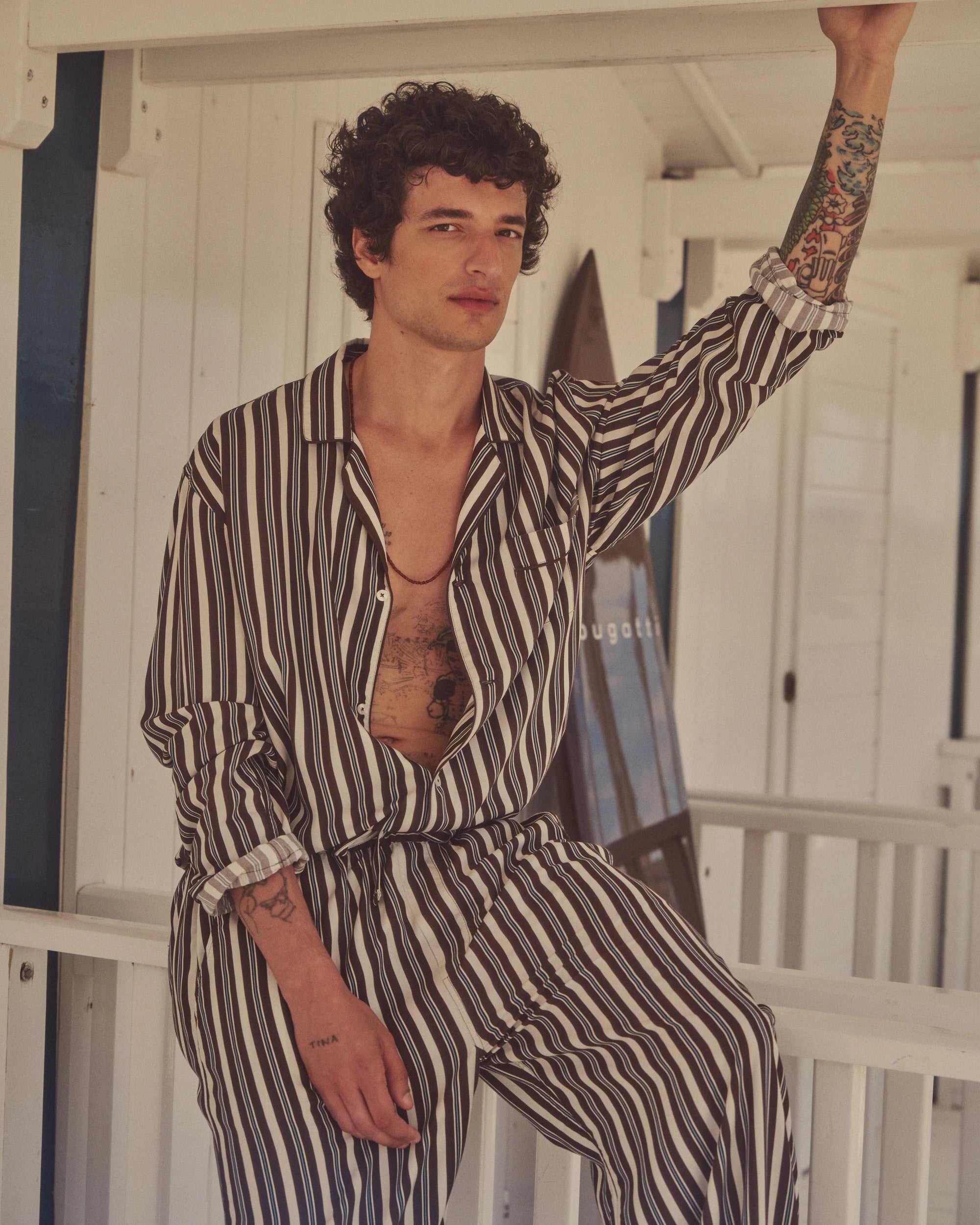 Gestreiftes bugatti Pyjama-Set in Schwarz-Weiß auf Model, lässig lehnend.