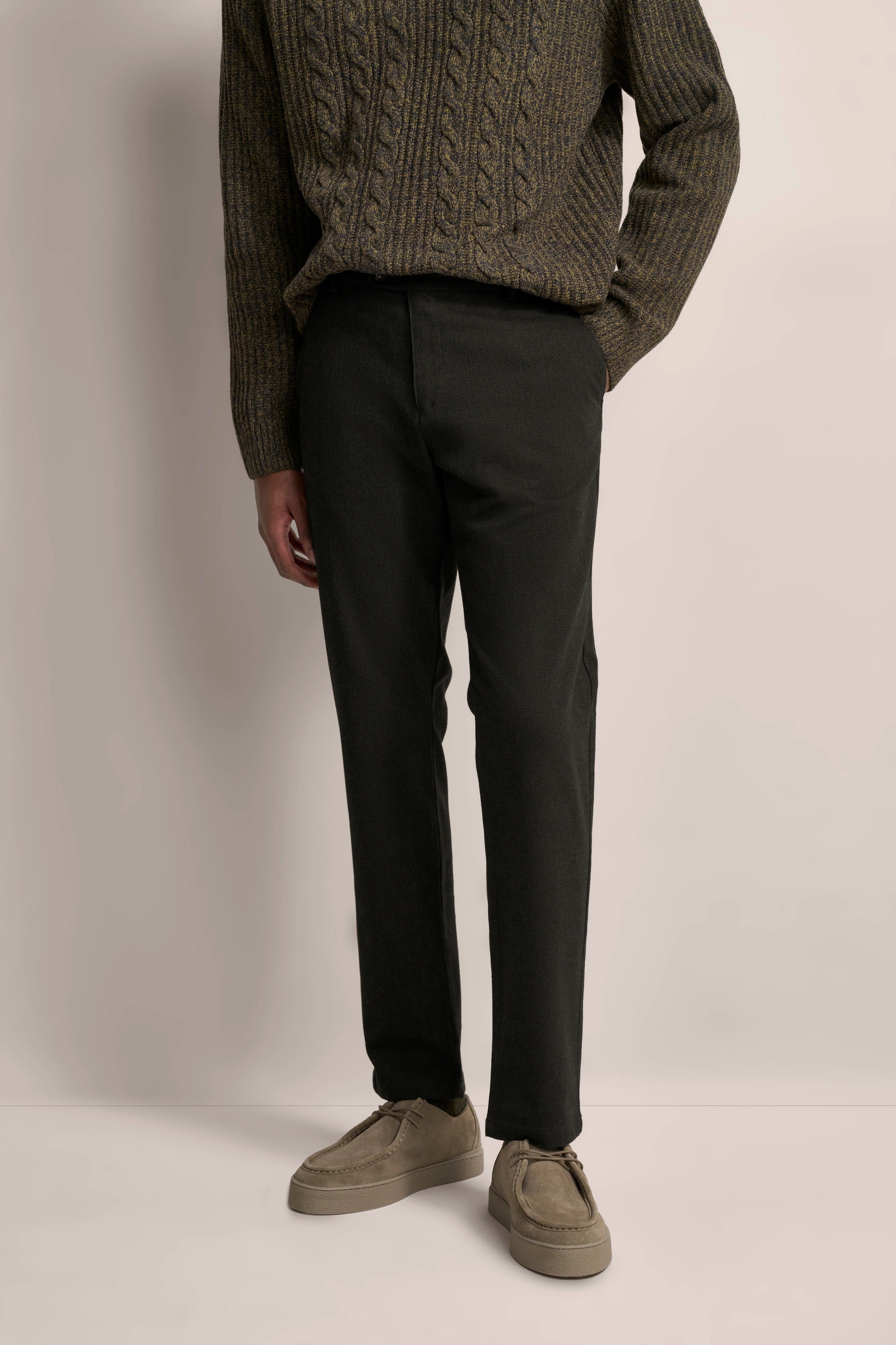 Strickpullover in Oliv mit schwarzer Hose, legeres Modelbild, lässige Pose.