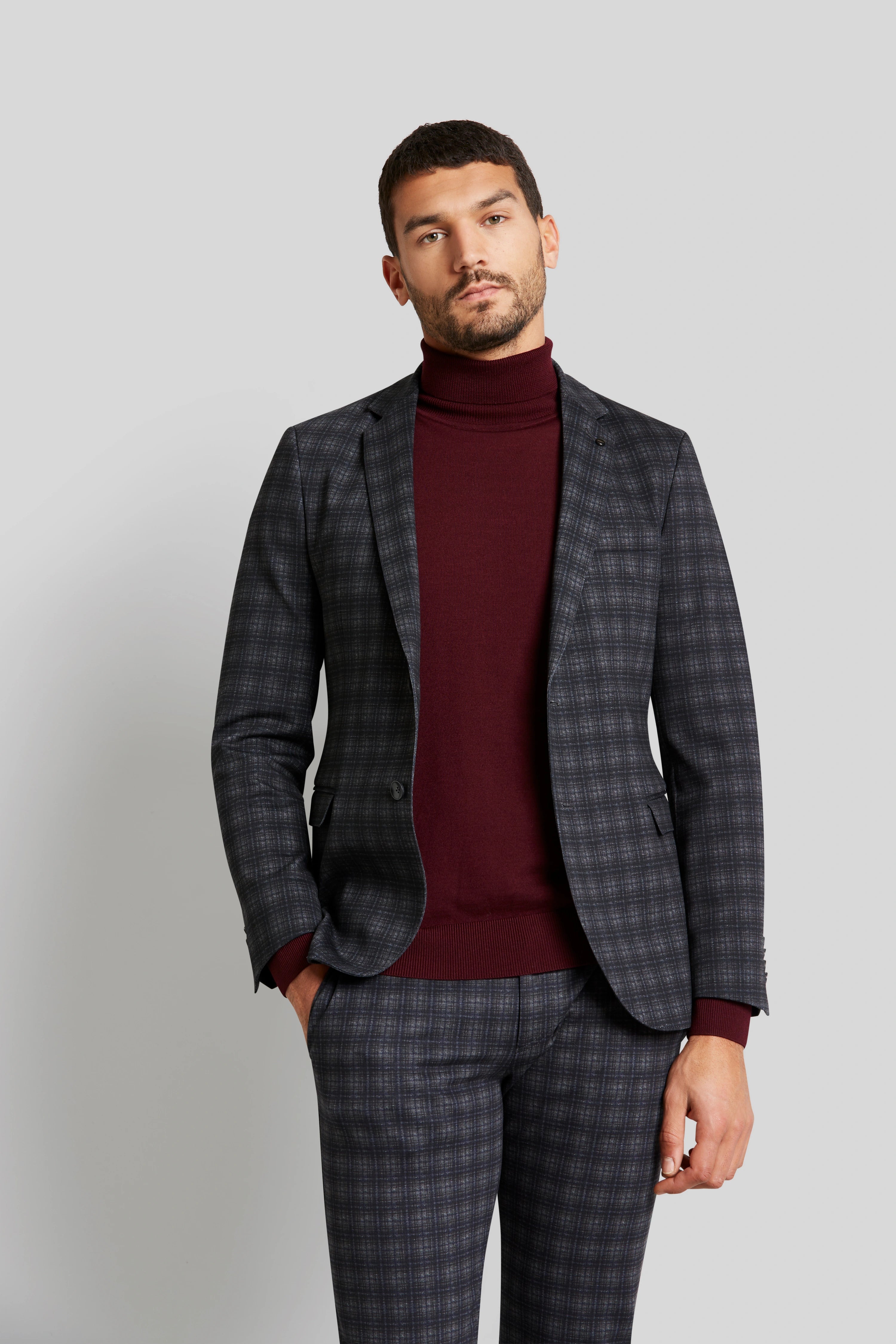 "Model in kariertem Anzug und burgunderrotem Rollkragenpullover von bugatti, legeres Posing."