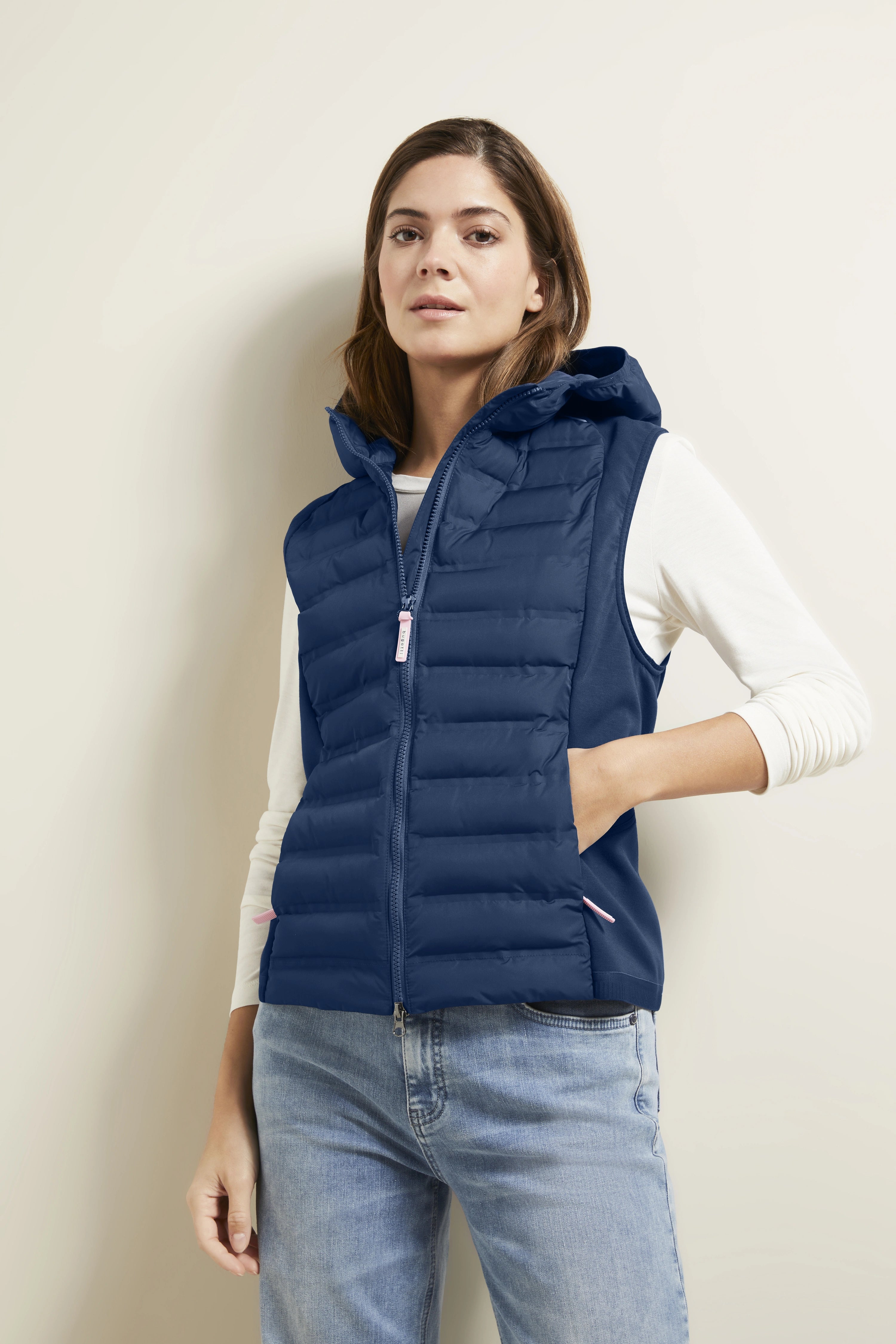 Model draagt blauwe gewatteerde bodywarmer van bugatti over wit shirt, casual look.
