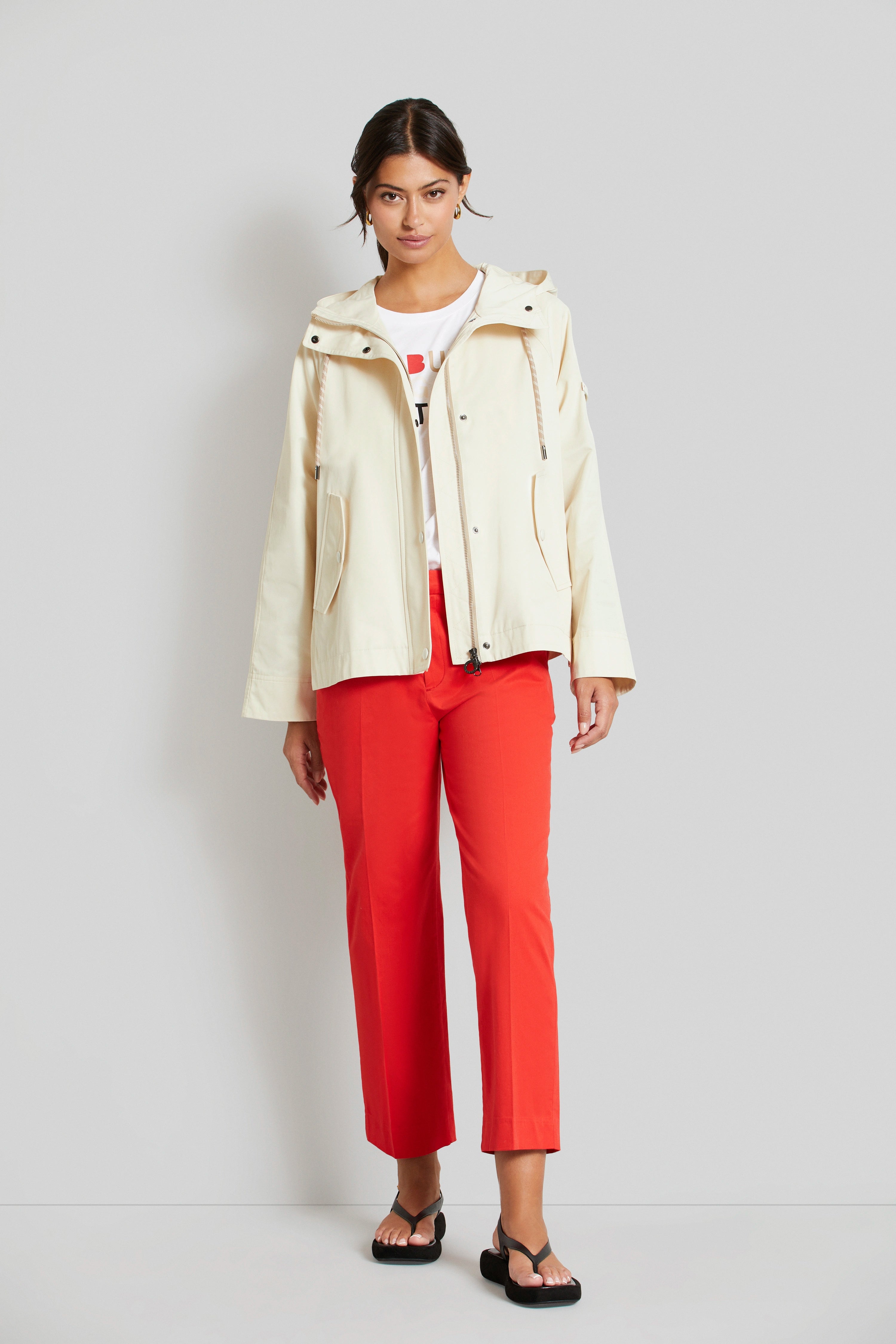 Model in cremefarbener Jacke, roter Hose, schwarzer Sandale