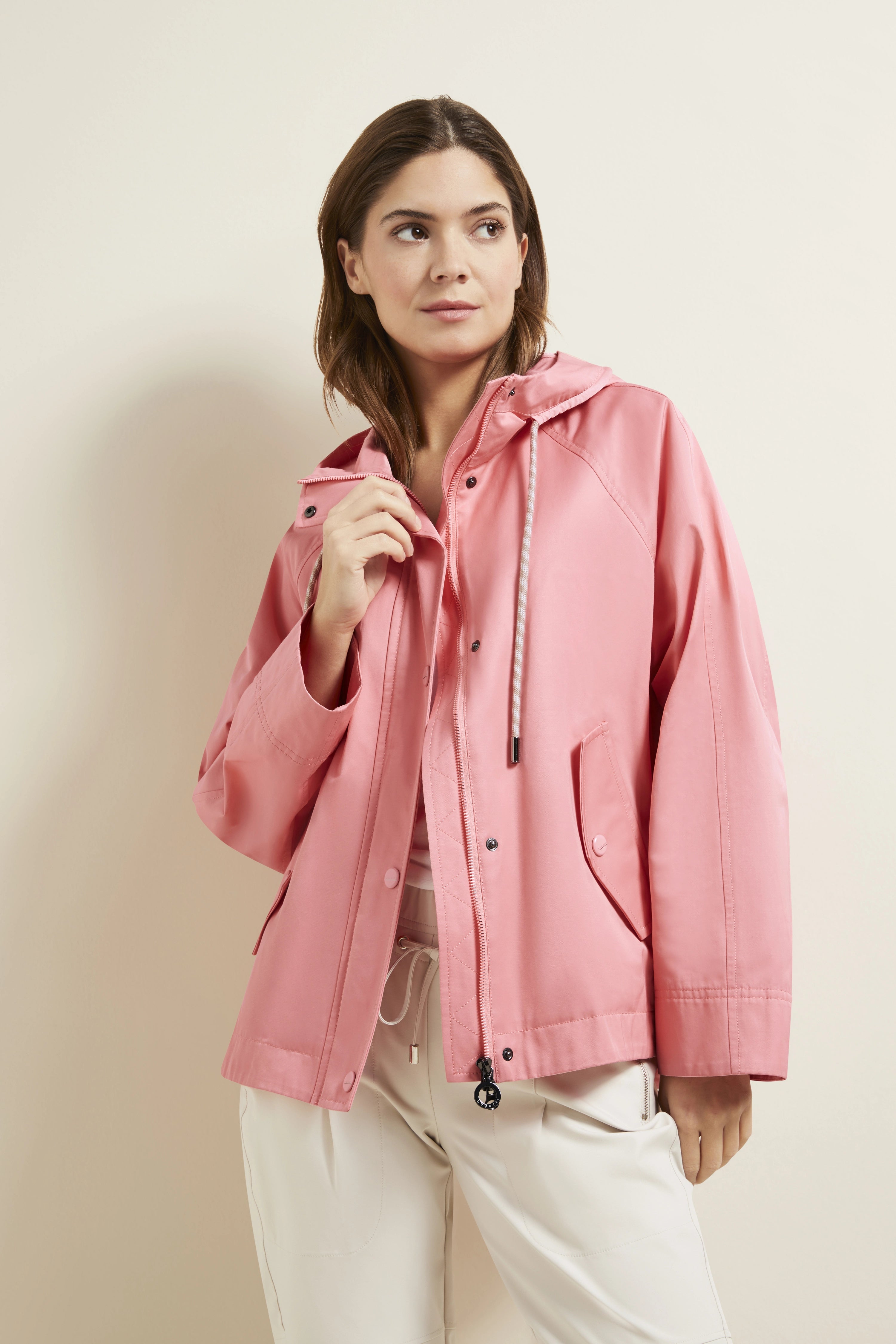 Model trägt rosa bugatti Jacke, Posing mit entspannter Handhaltung, kombiniert mit heller Hose.
