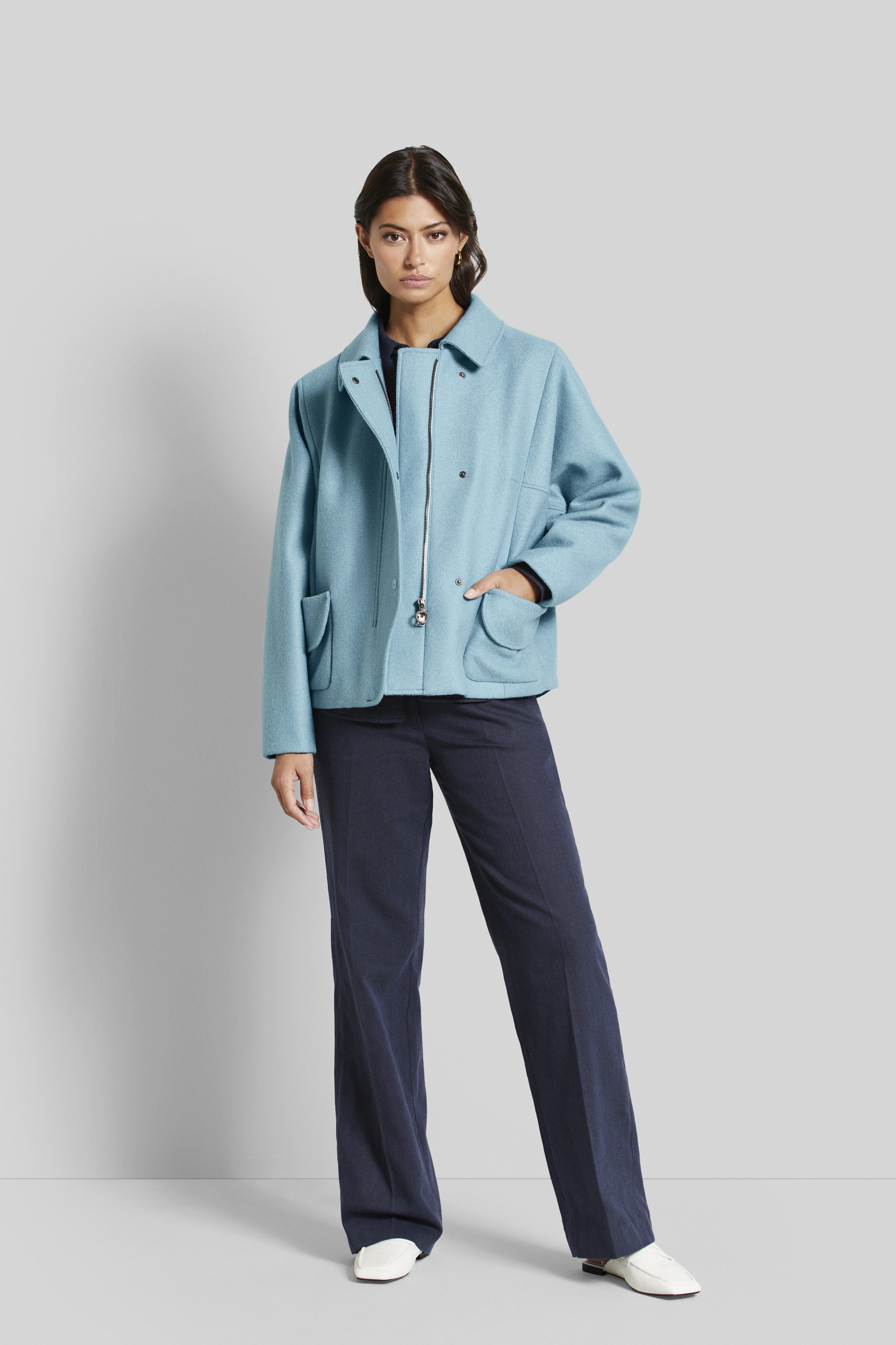 Model: Vrouw in lichtblauwe bugatti jas, donkerblauwe broek, witte schoenen