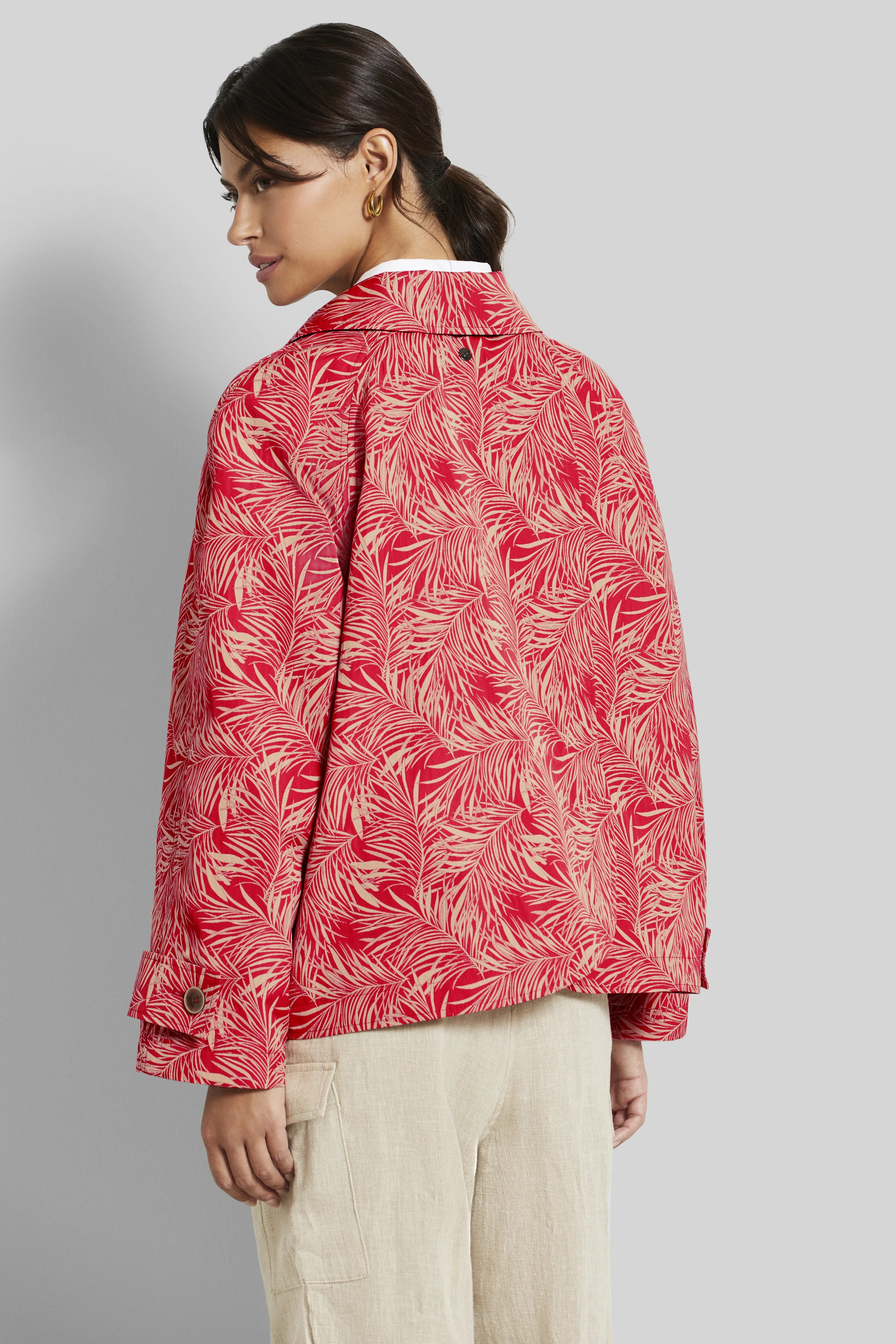 Model in roter bugatti Jacke mit Blattmuster, beige Hose, seitliche Rückansicht.