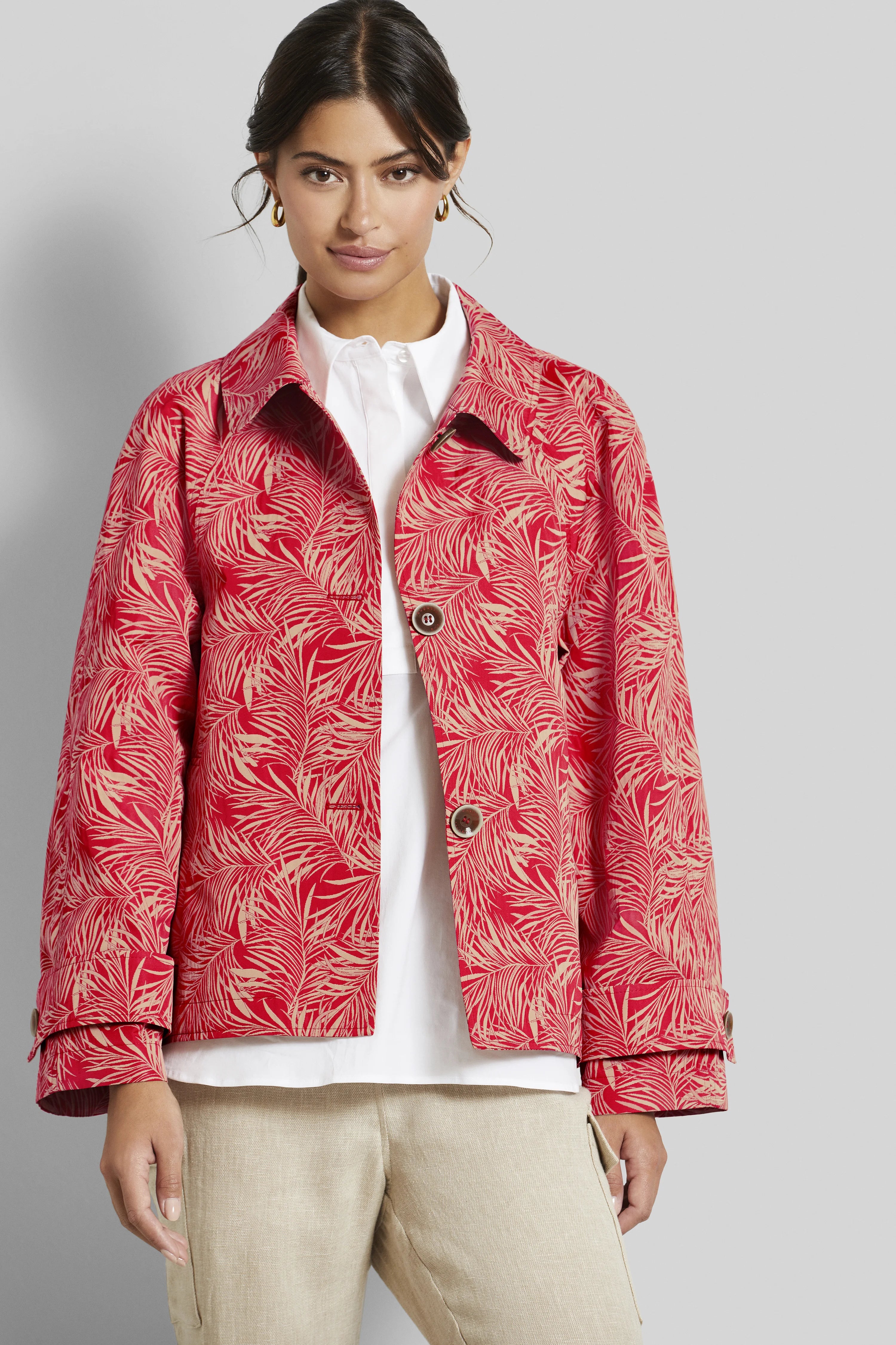 Rotes bugatti-Jackett mit Blattmuster, weißer Bluse und beige Hose, Model frontal stehend.