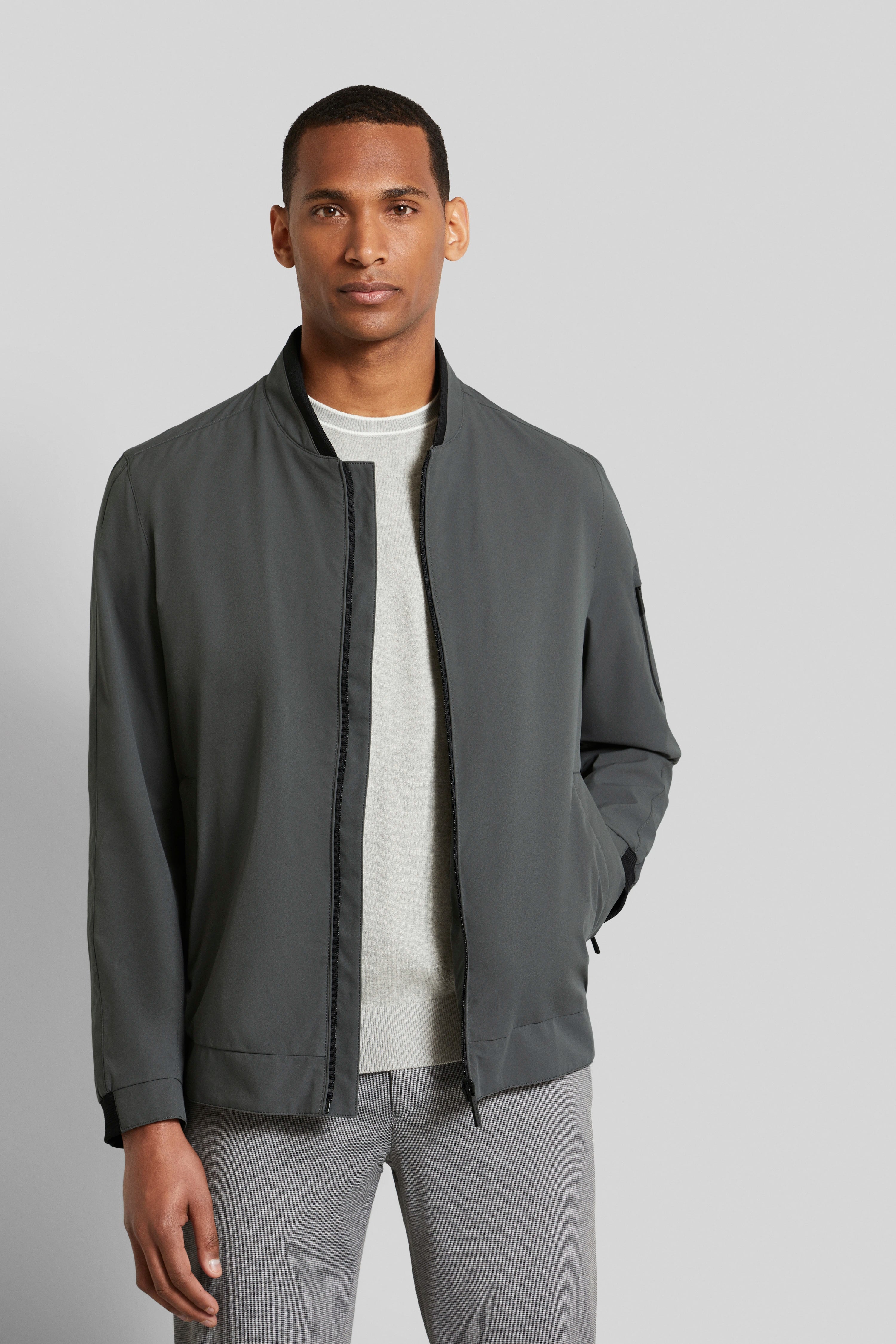 Graue Jacke, grauer Pullover, graue Hose, Modelbild, entspannte Haltung.
