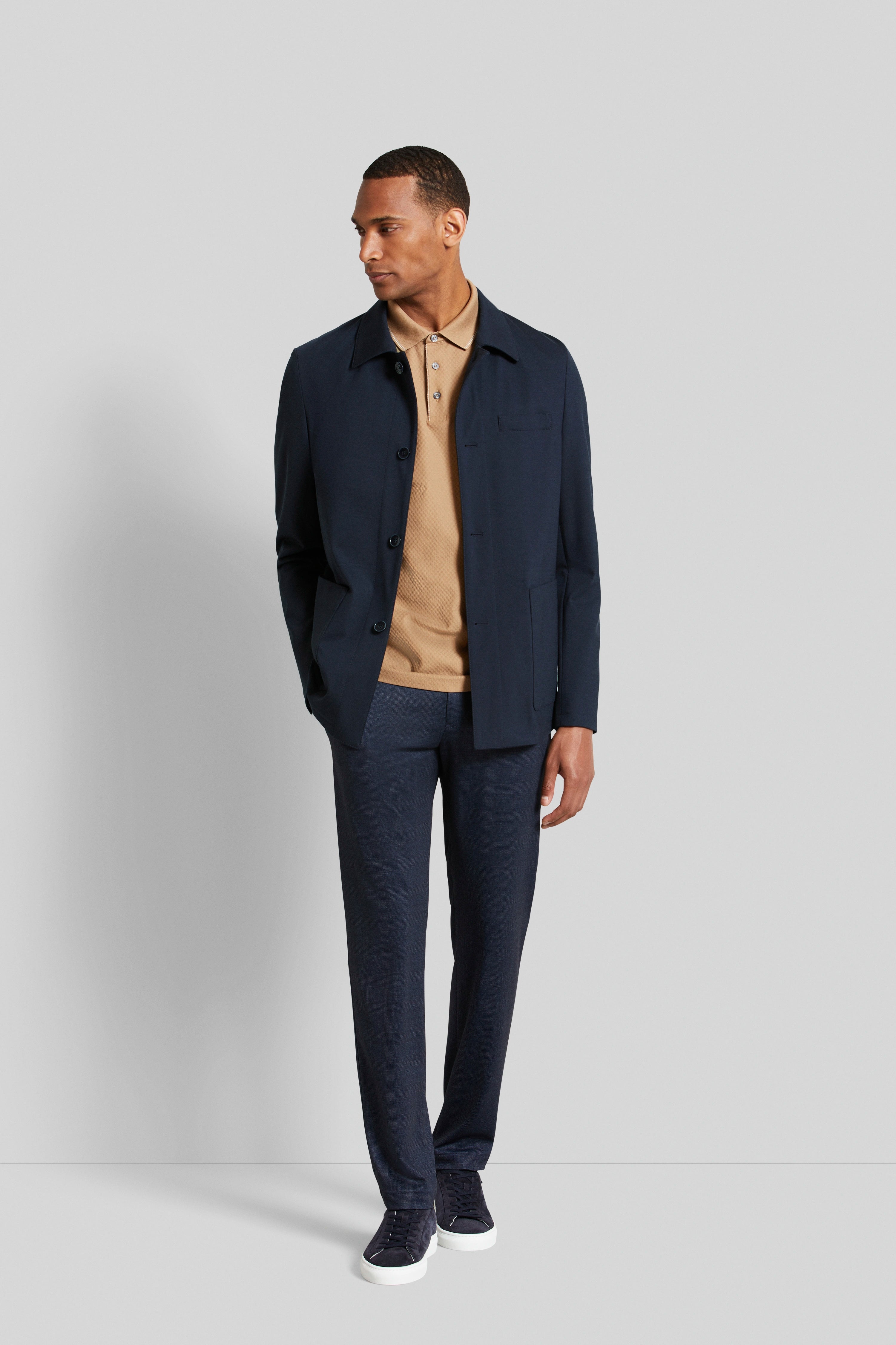 bugatti model: man draagt donkerblauwe jas, beige polo, donkerblauwe broek