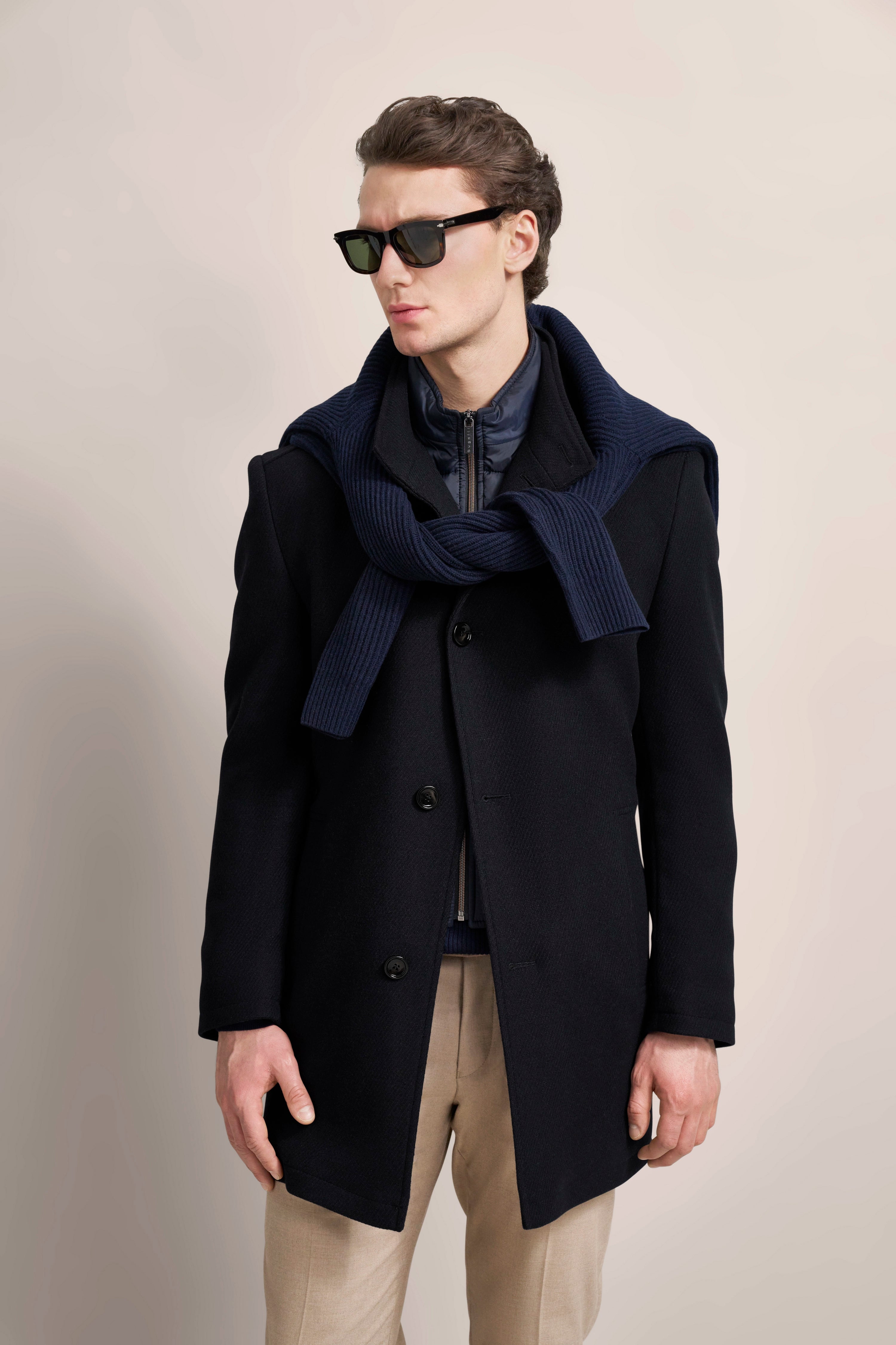 Model in marineblauem bugatti-Mantel, blauer Schal, beige Hose, Sonnenbrille