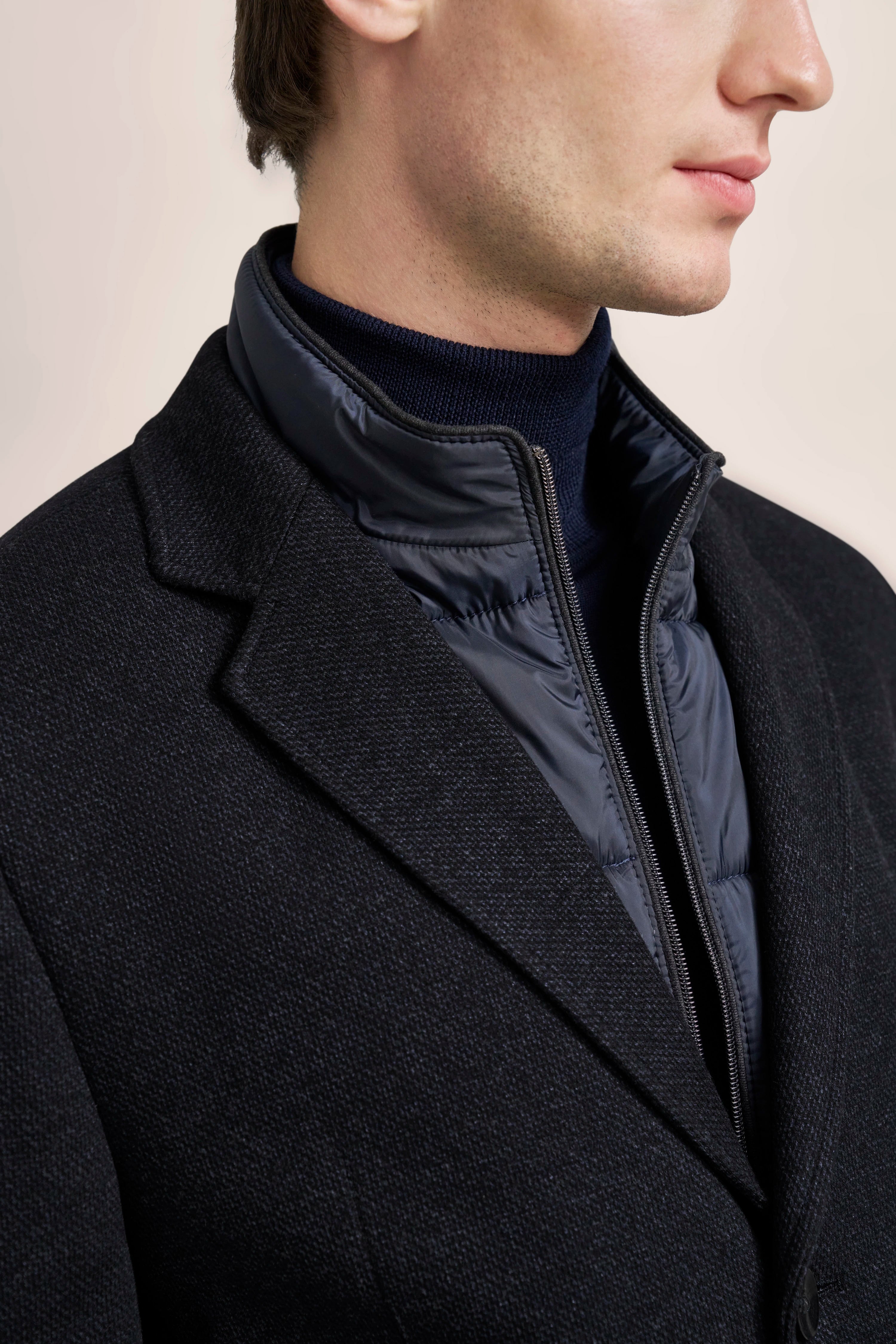 Büstenbild mit schwarzem bugatti Blazer, darunter dunkelblauer Steppkragen und Rollkragenpullover.