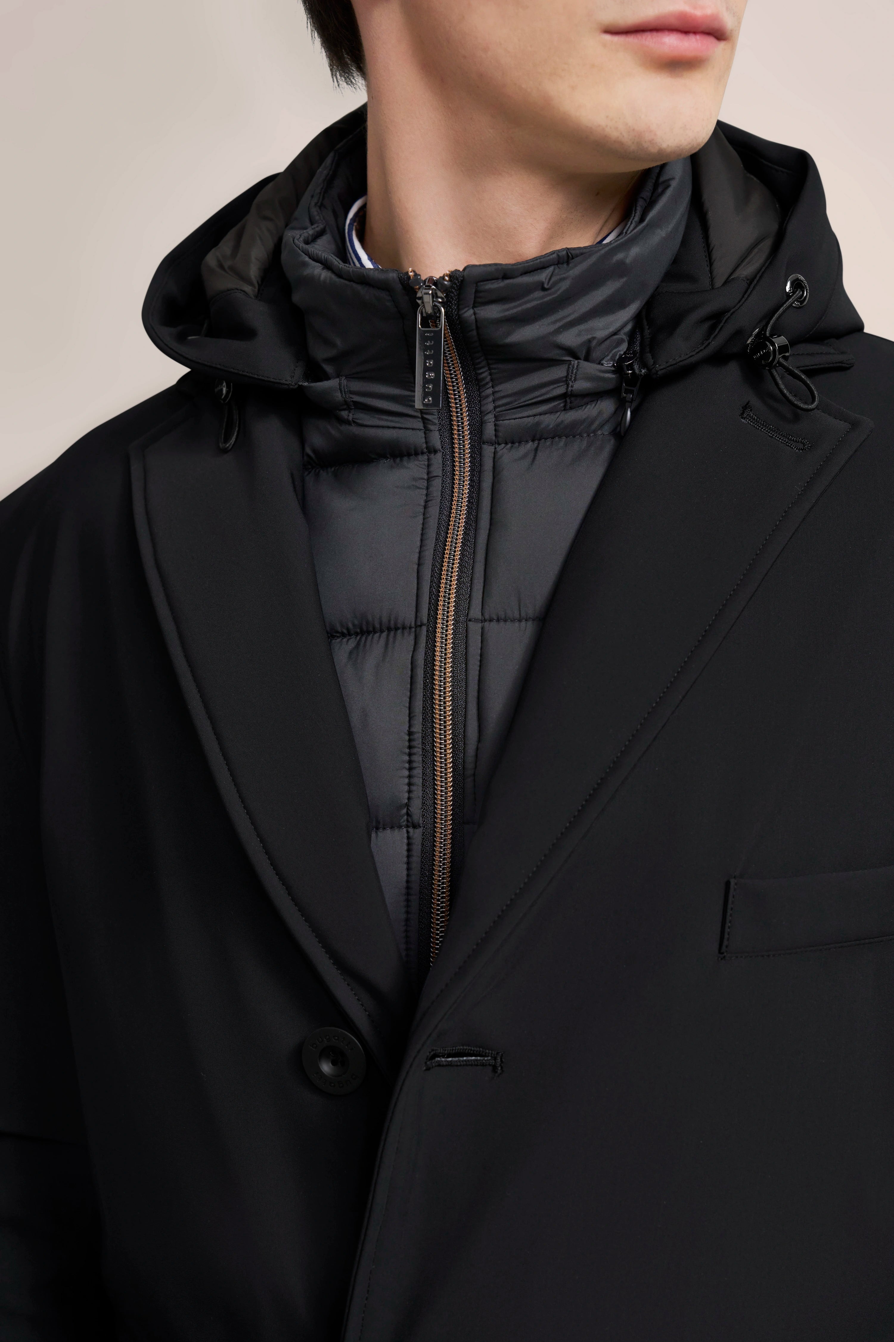 Schwarzer bugatti Mantel mit Steppjacke in Lagenlook, Modelbild, lässige seitliche Pose.
