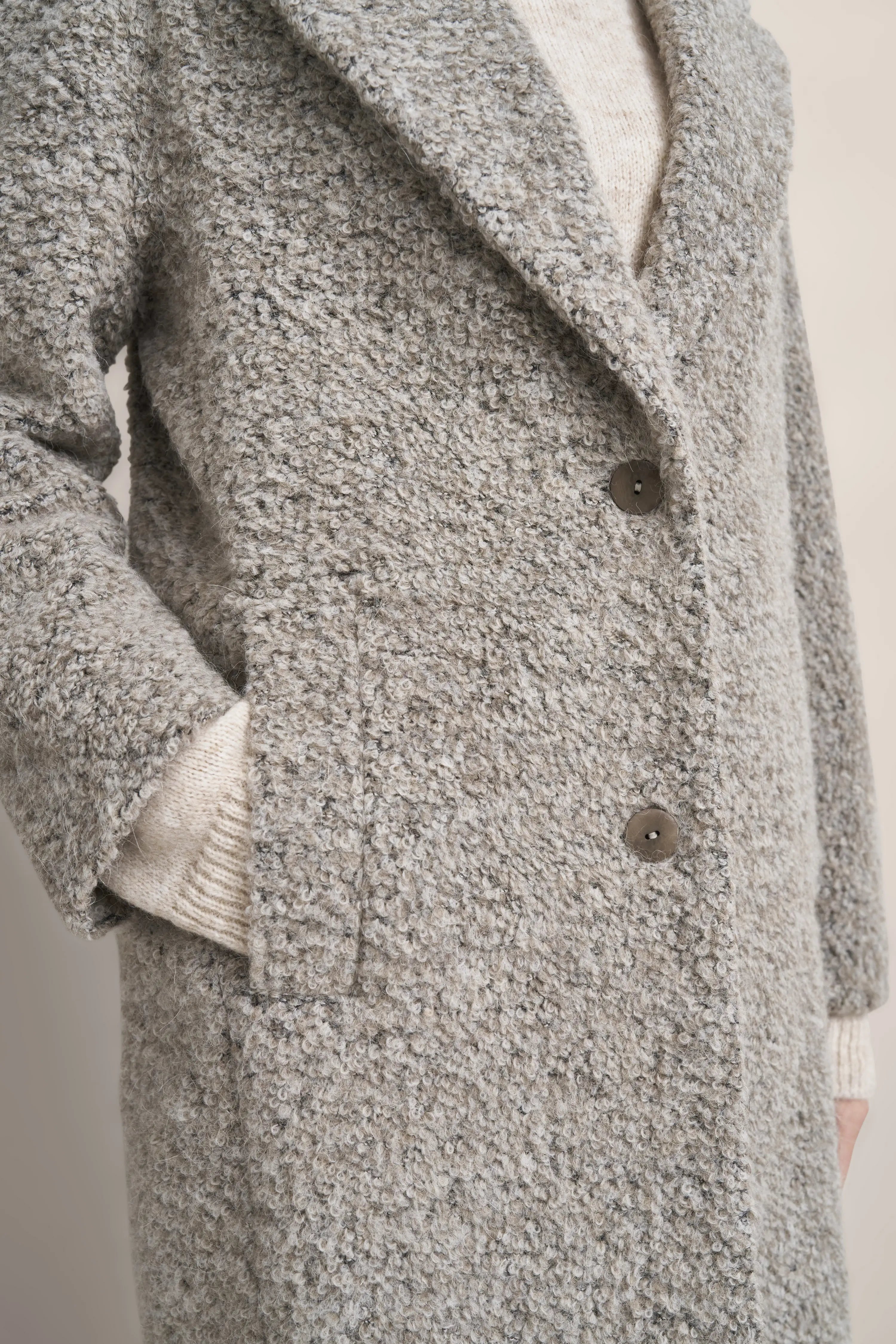 Grauer Bouclé-Mantel von bugatti, Nahaufnahme, beige Strickpullover darunter sichtbar.