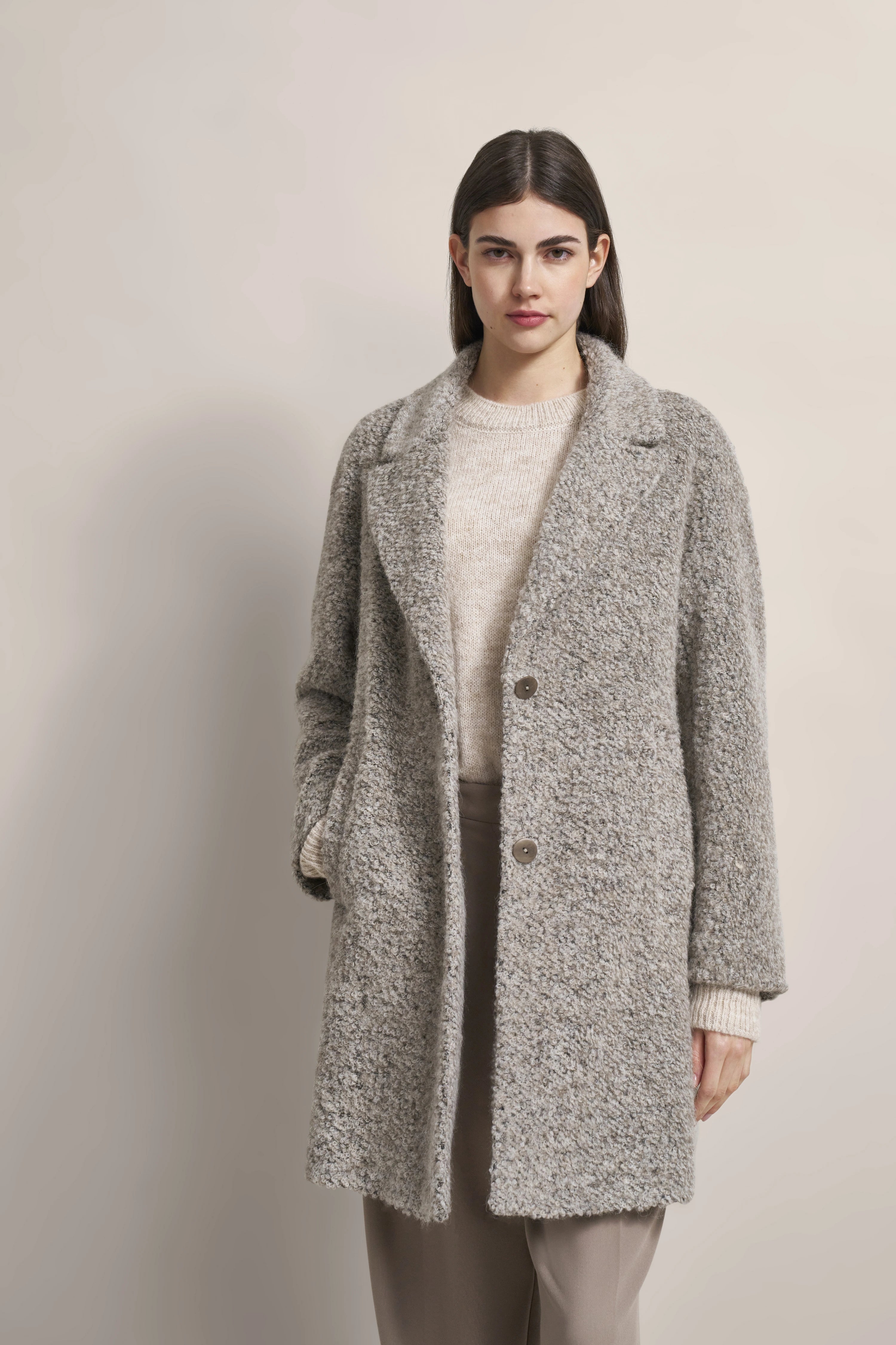 Grauer bouclé Mantel von bugatti, beige Strickpullover, Modelbild, entspannte Pose.