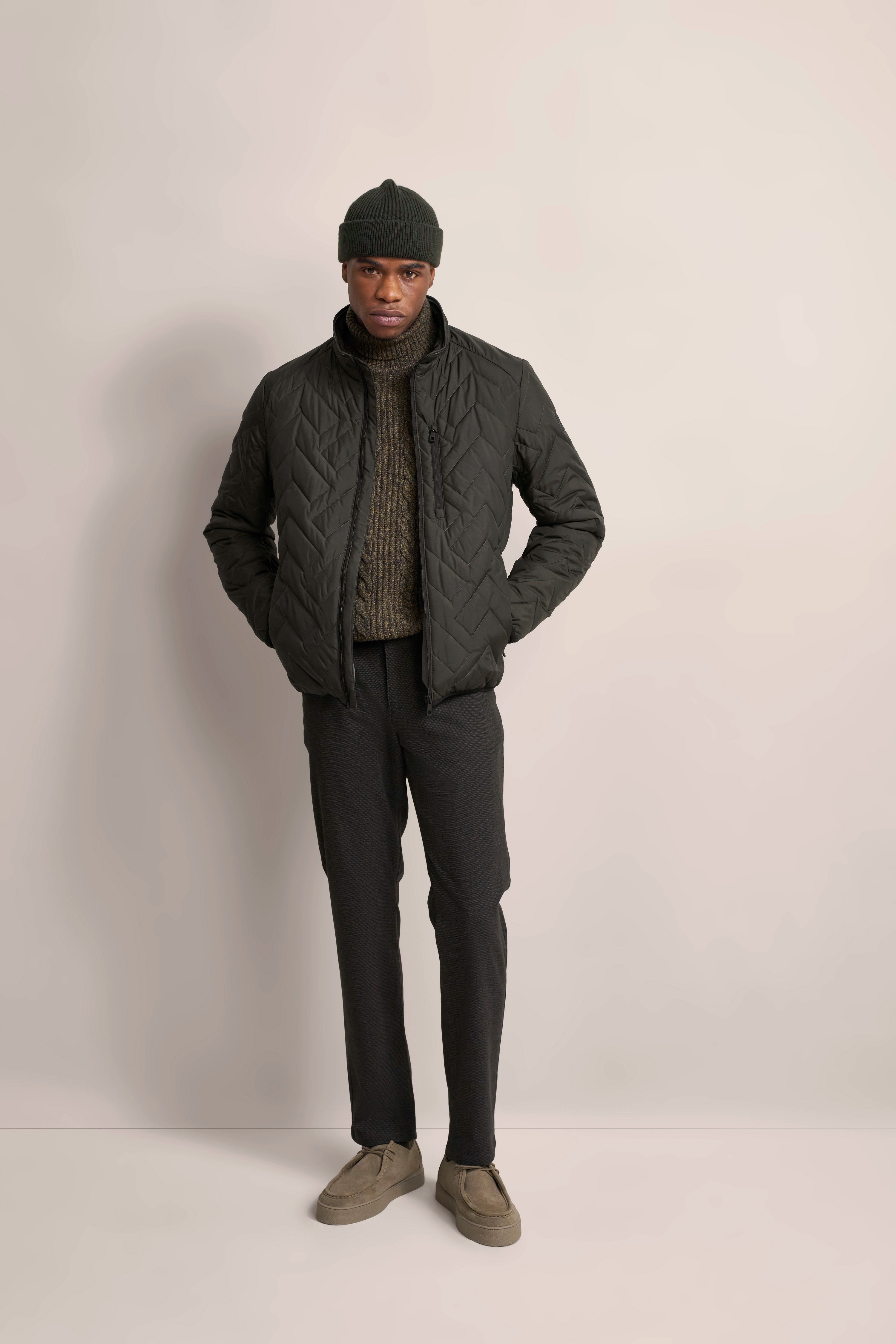 Model trägt olivgrüne Steppjacke, braunen Strickpullover, dunkelgraue Hose, Mütze