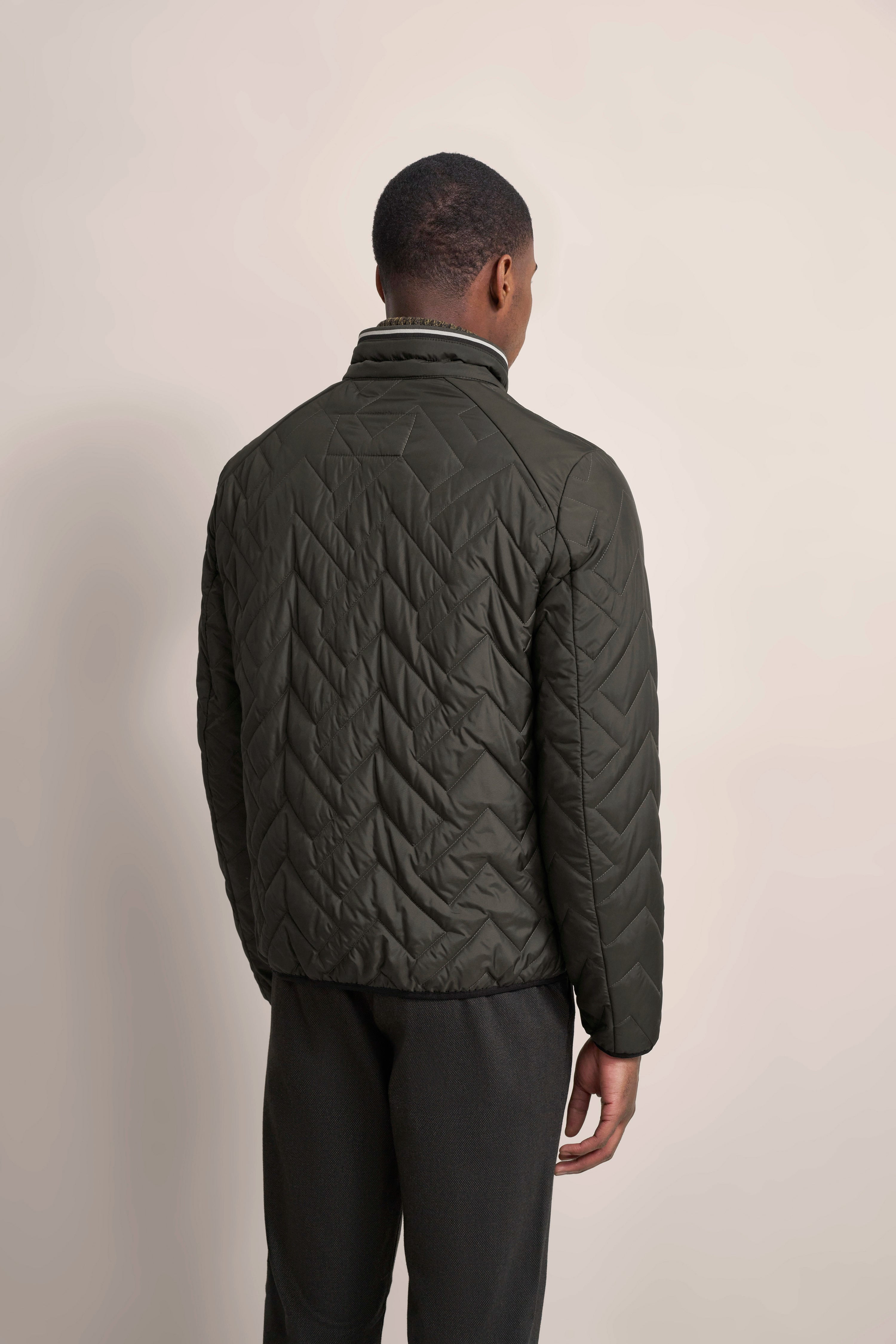 Dunkelgrüne Steppjacke, Rückansicht auf Model, entspannte Pose, bugatti Stil.