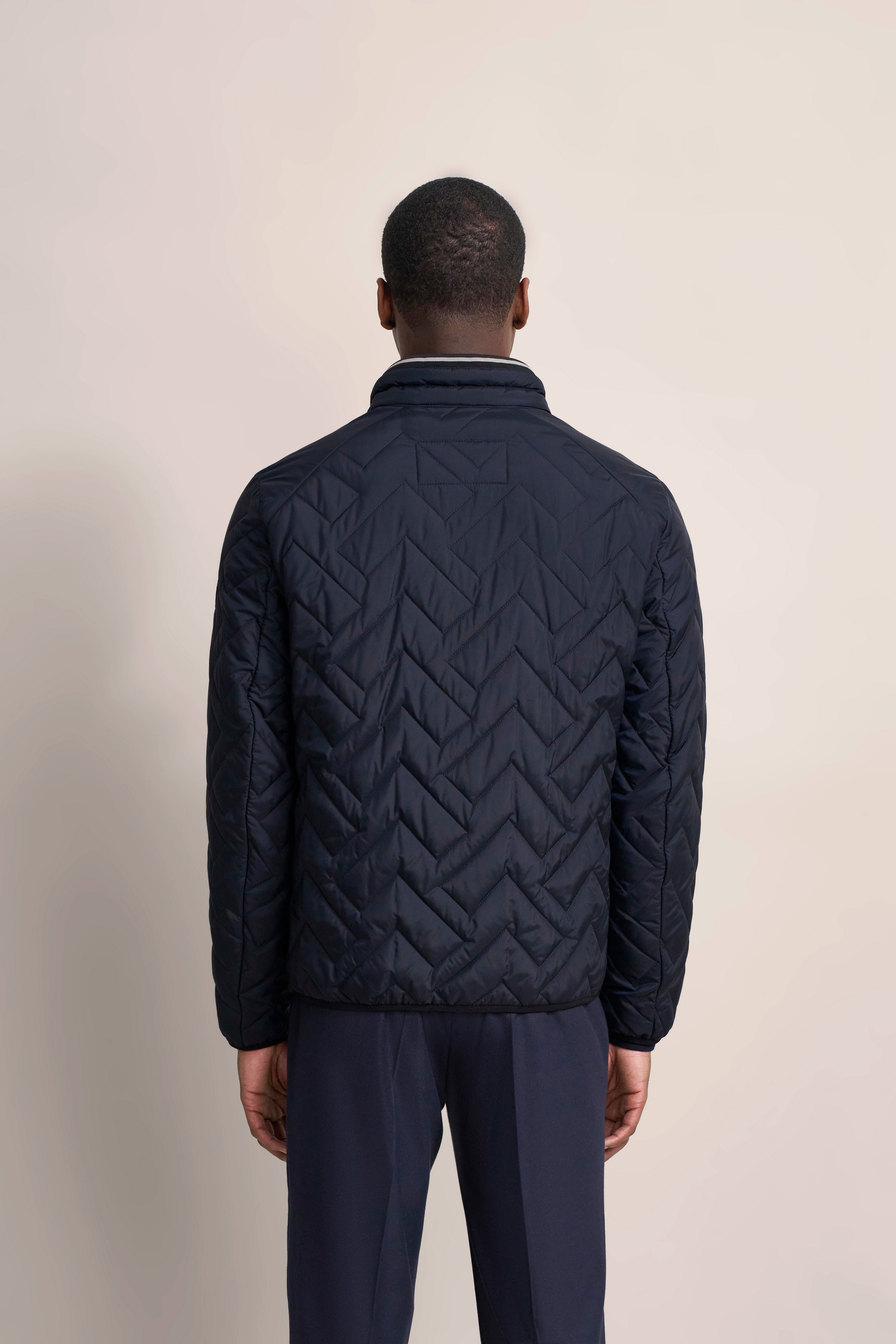 Navy gesteppte Jacke, Rückansicht, auf Model. Eleganz und Komfort von bugatti.