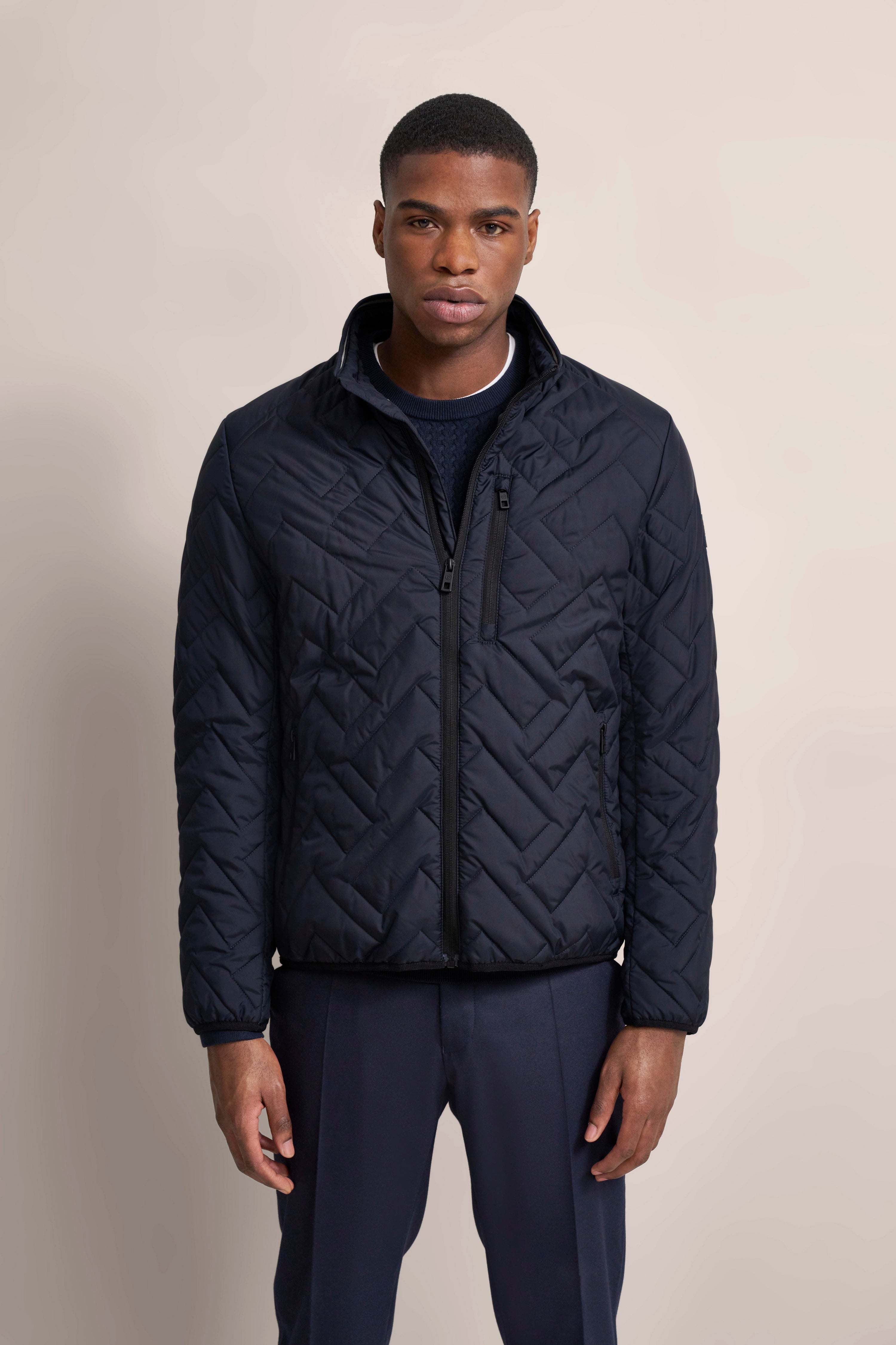 Model in navy Steppjacke und Hose, frontal, legeres Posing.