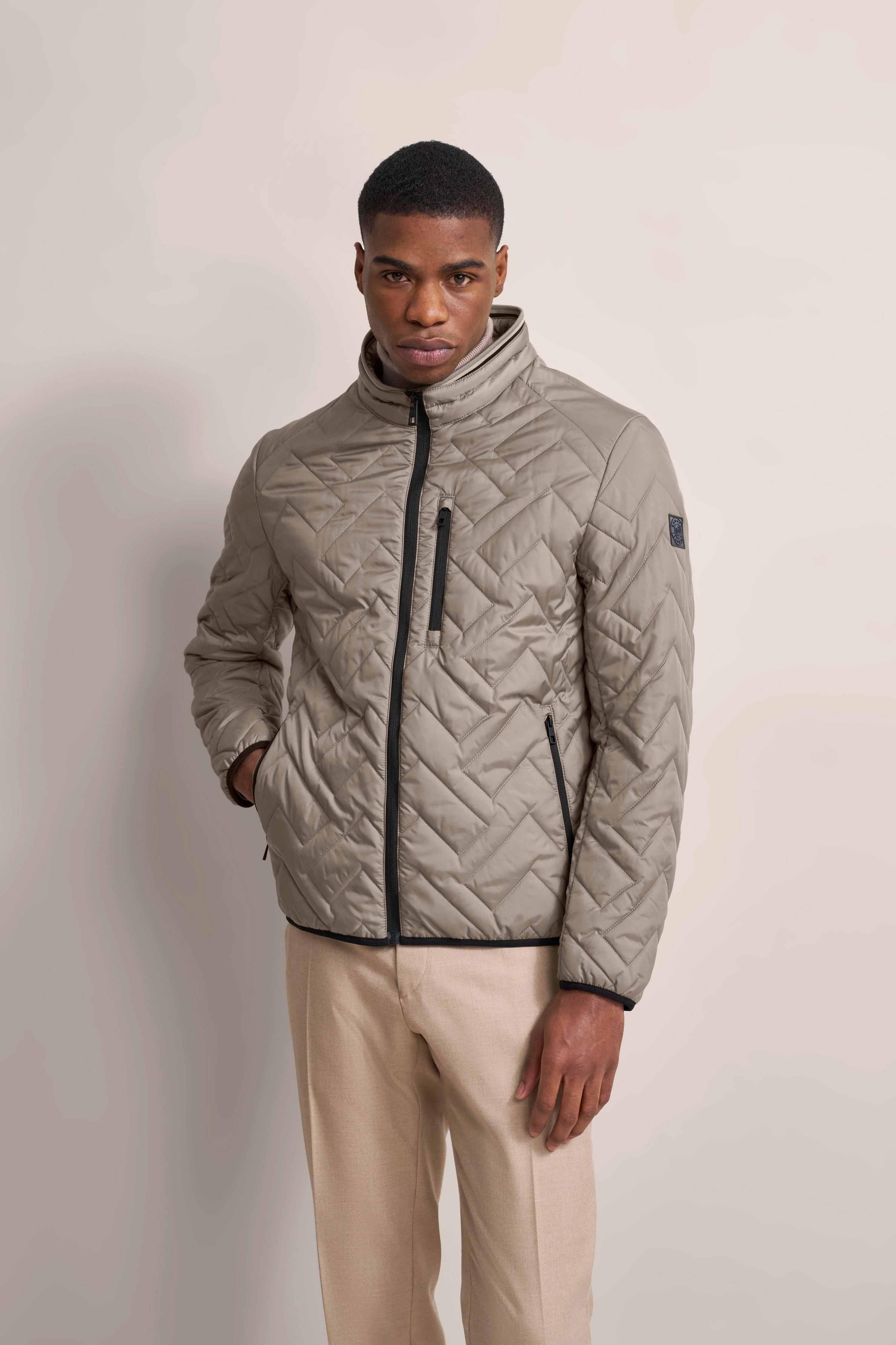 Steppjacke in Beige von bugatti, Modelbild, Hände in den Taschen, entspannte Pose.