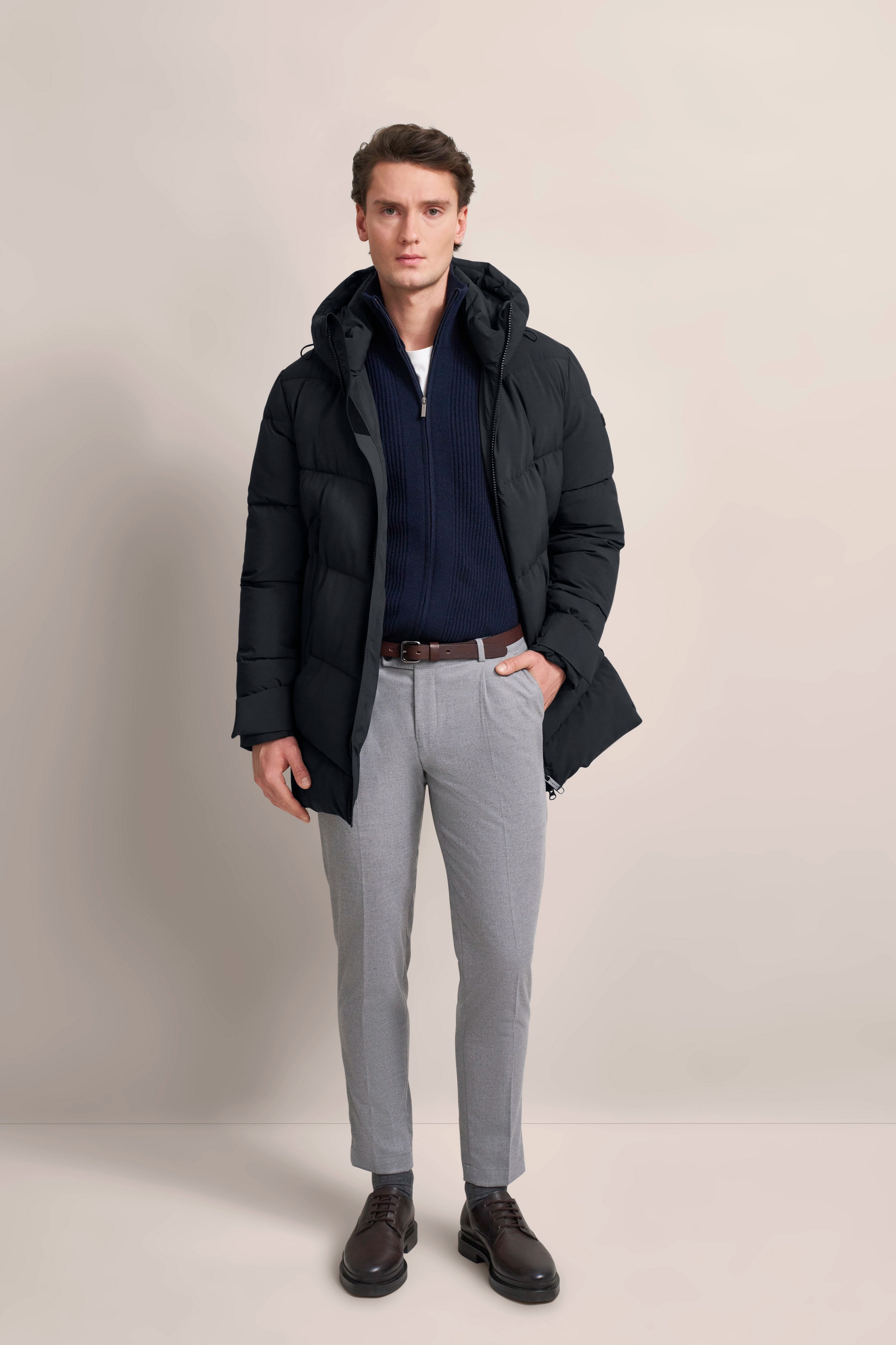 Model trägt schwarze bugatti Jacke, blauen Pullover, graue Hose
