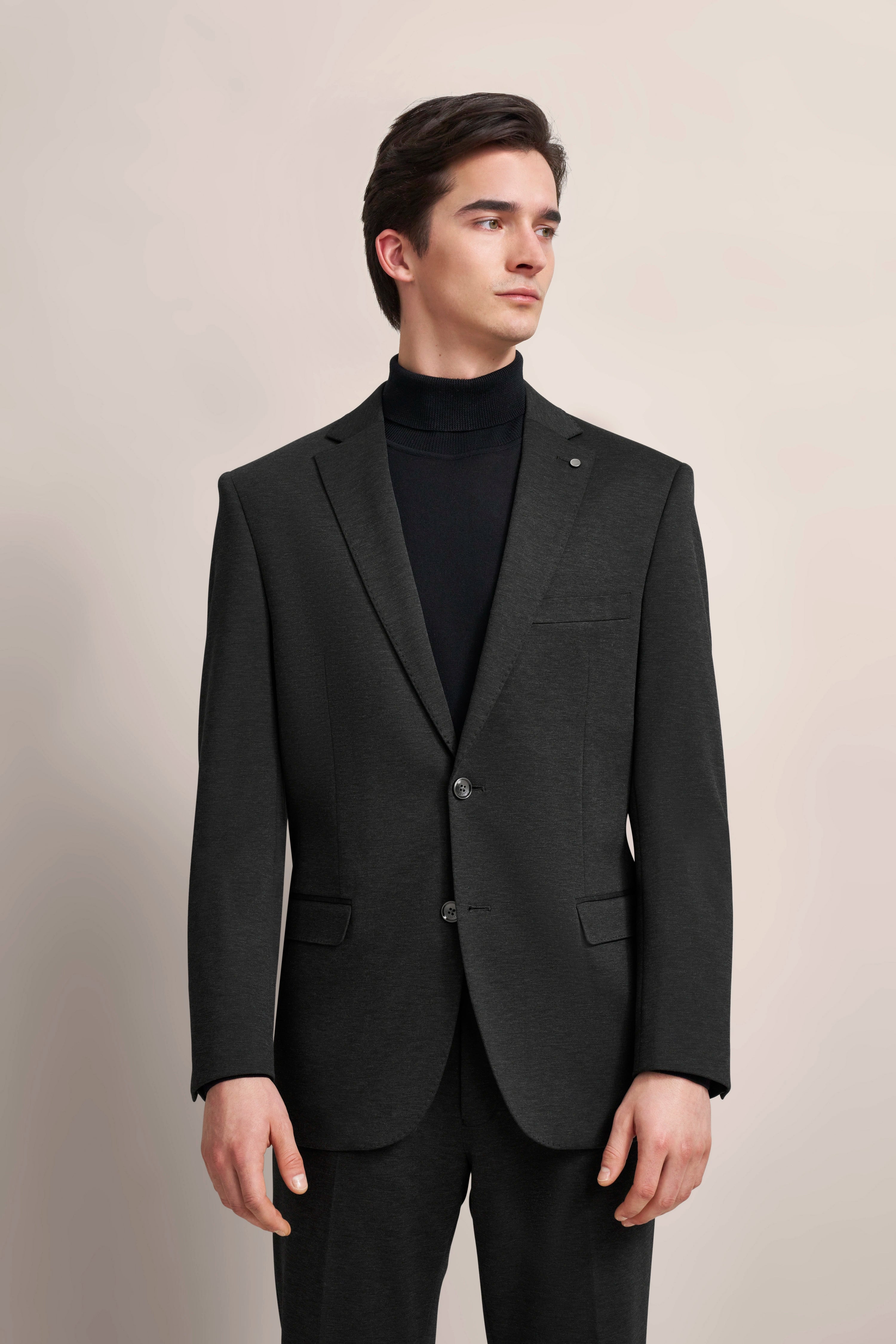 "bugatti Anzug in Schwarz, Rollkragenpullover, Modell posiert seitlich, eleganter Look."