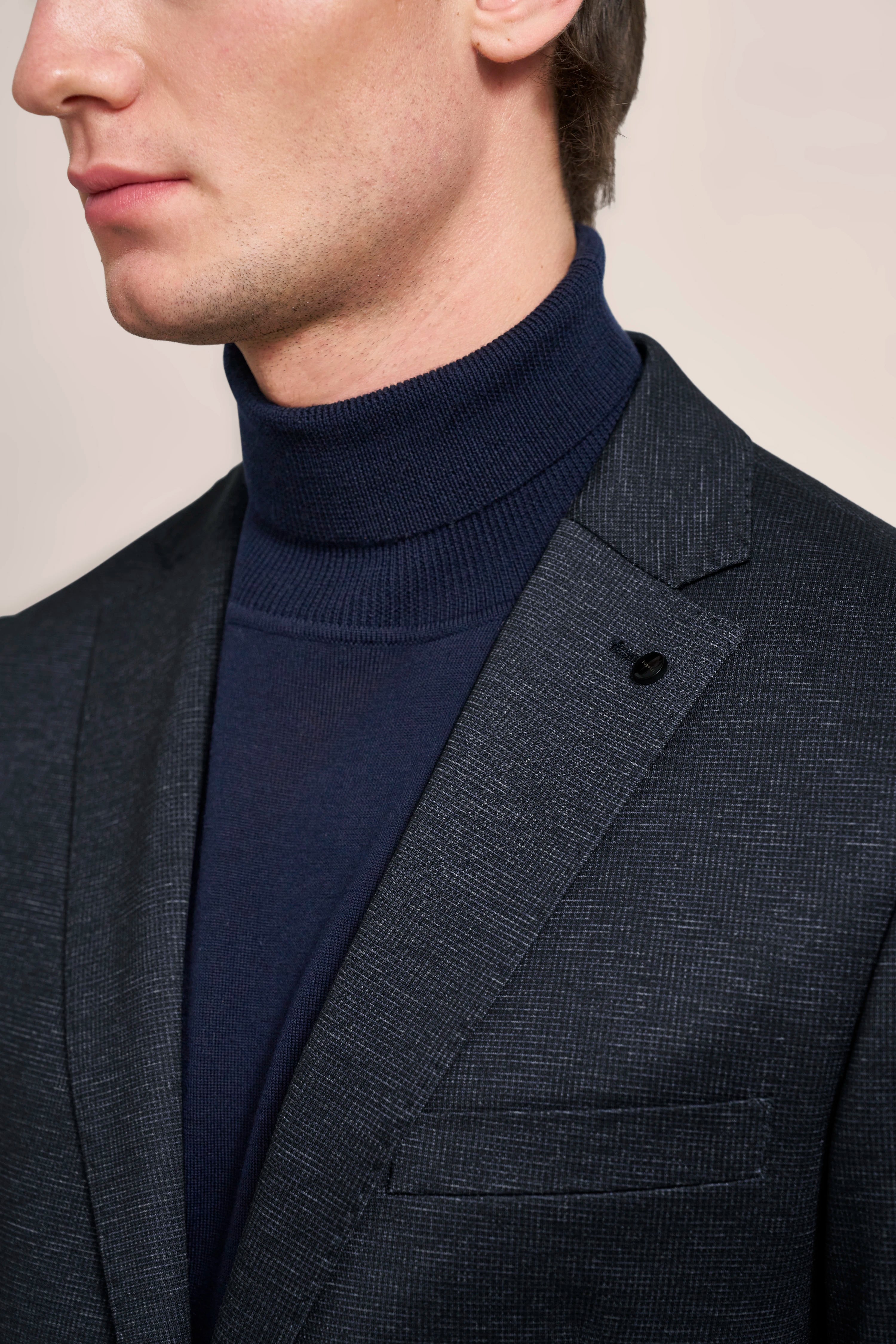 Close-up: Dark bugatti blazer with fine texture, paired with navy turtleneck sweater.