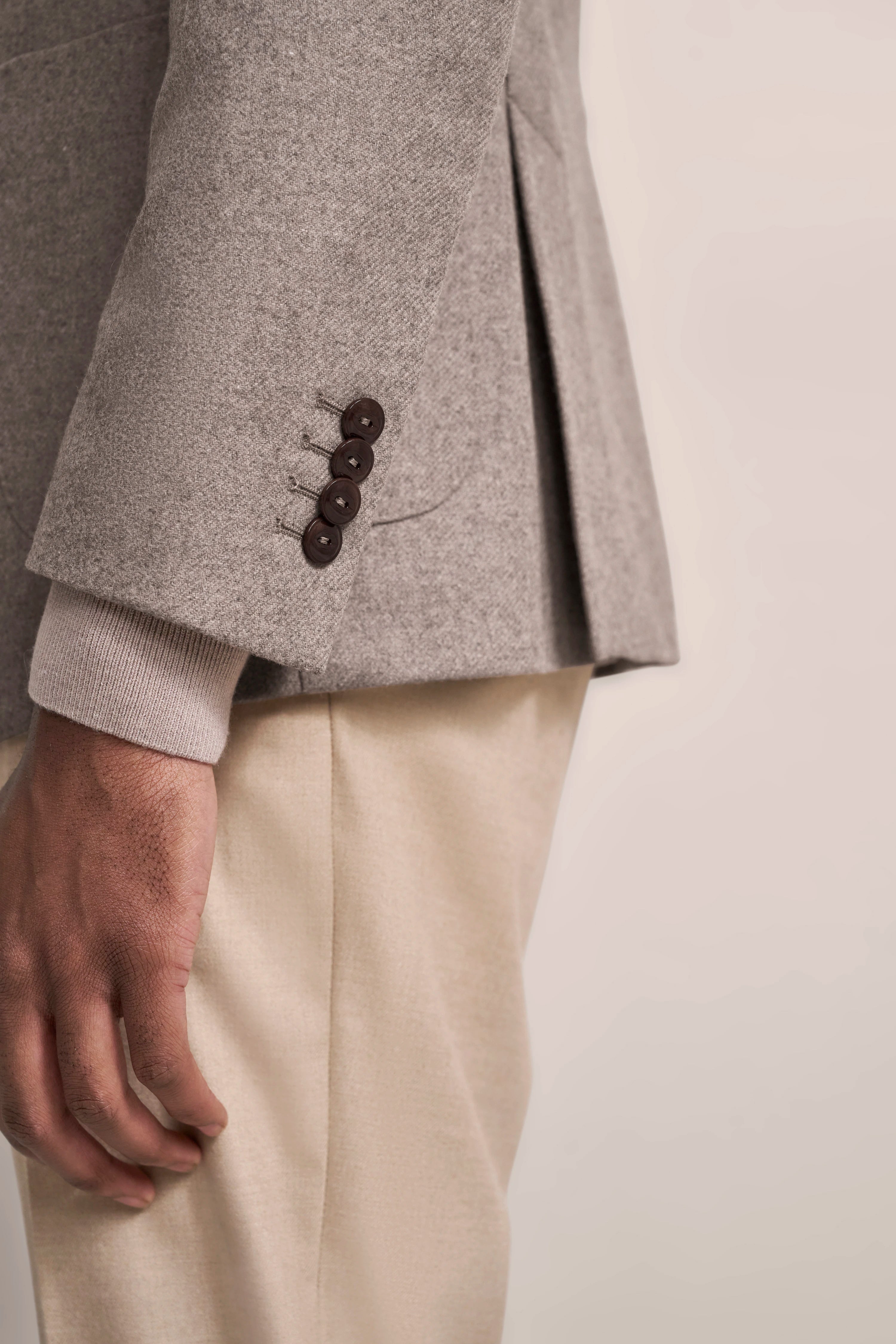 Gray bugatti blazer with brown buttons, paired with beige trousers. Close-up shot.