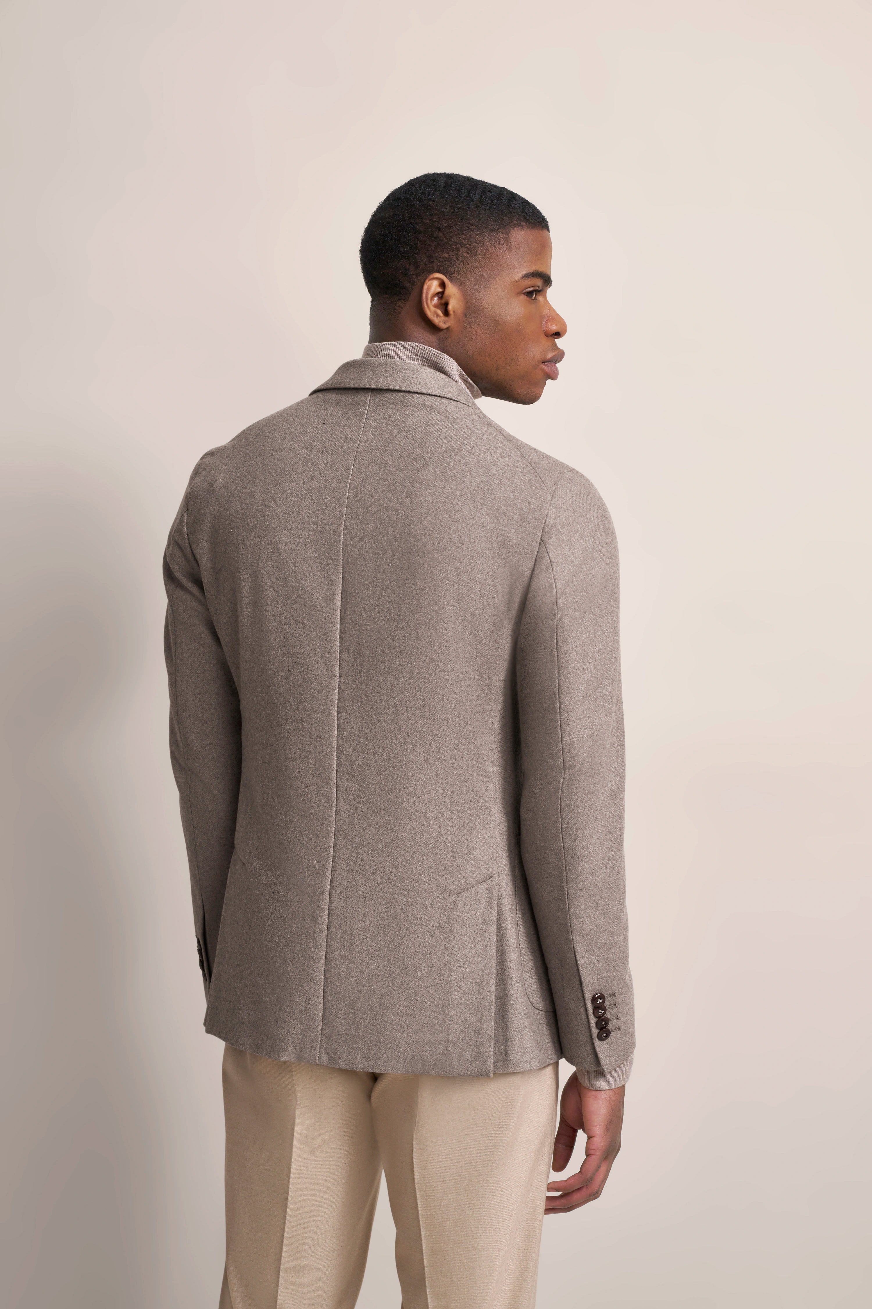 Back view of model in grey blazer and beige trousers, bugatti style, elegant pose.