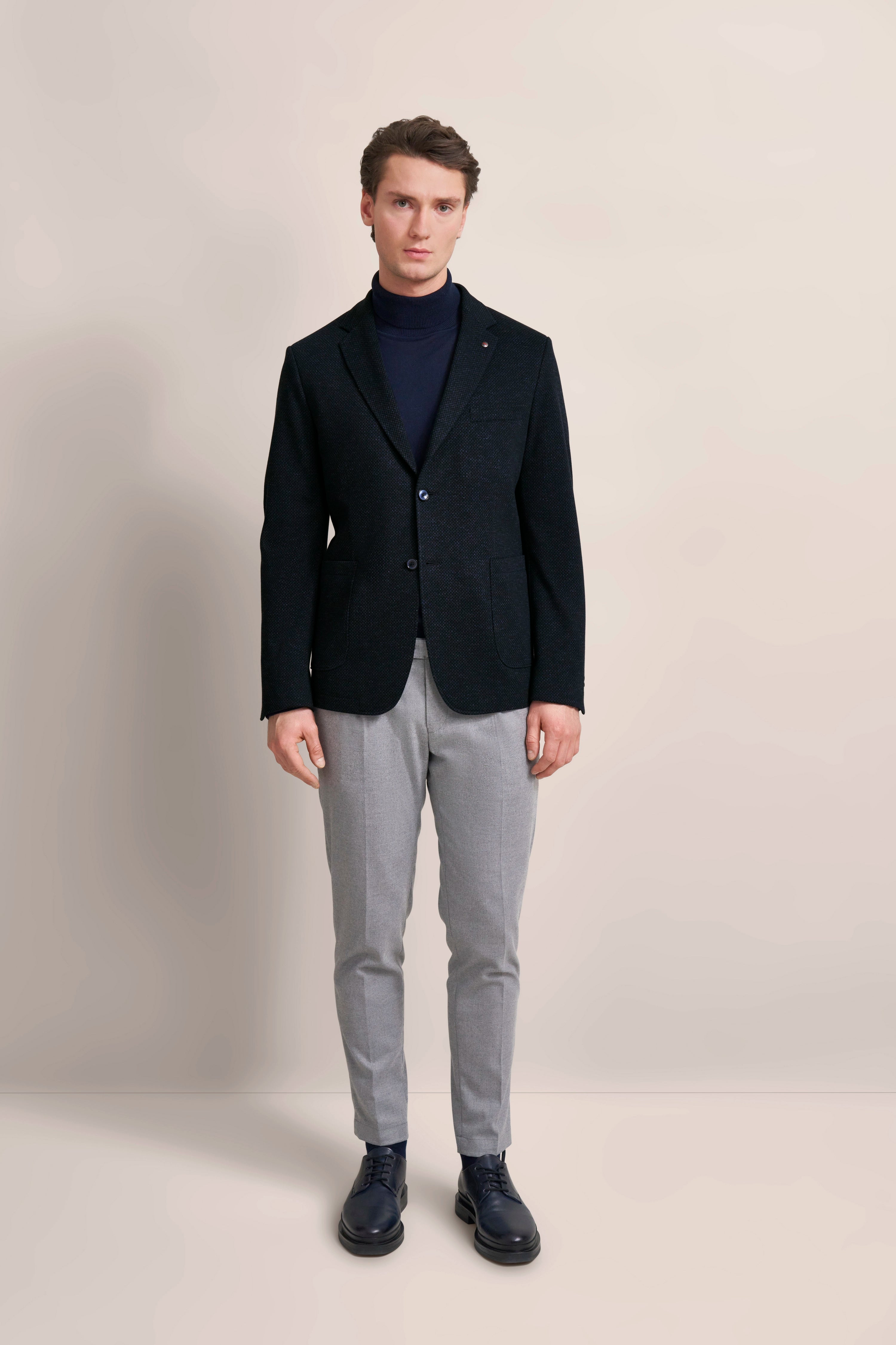 bugatti model in een donkerblauwe blazer en grijze broek