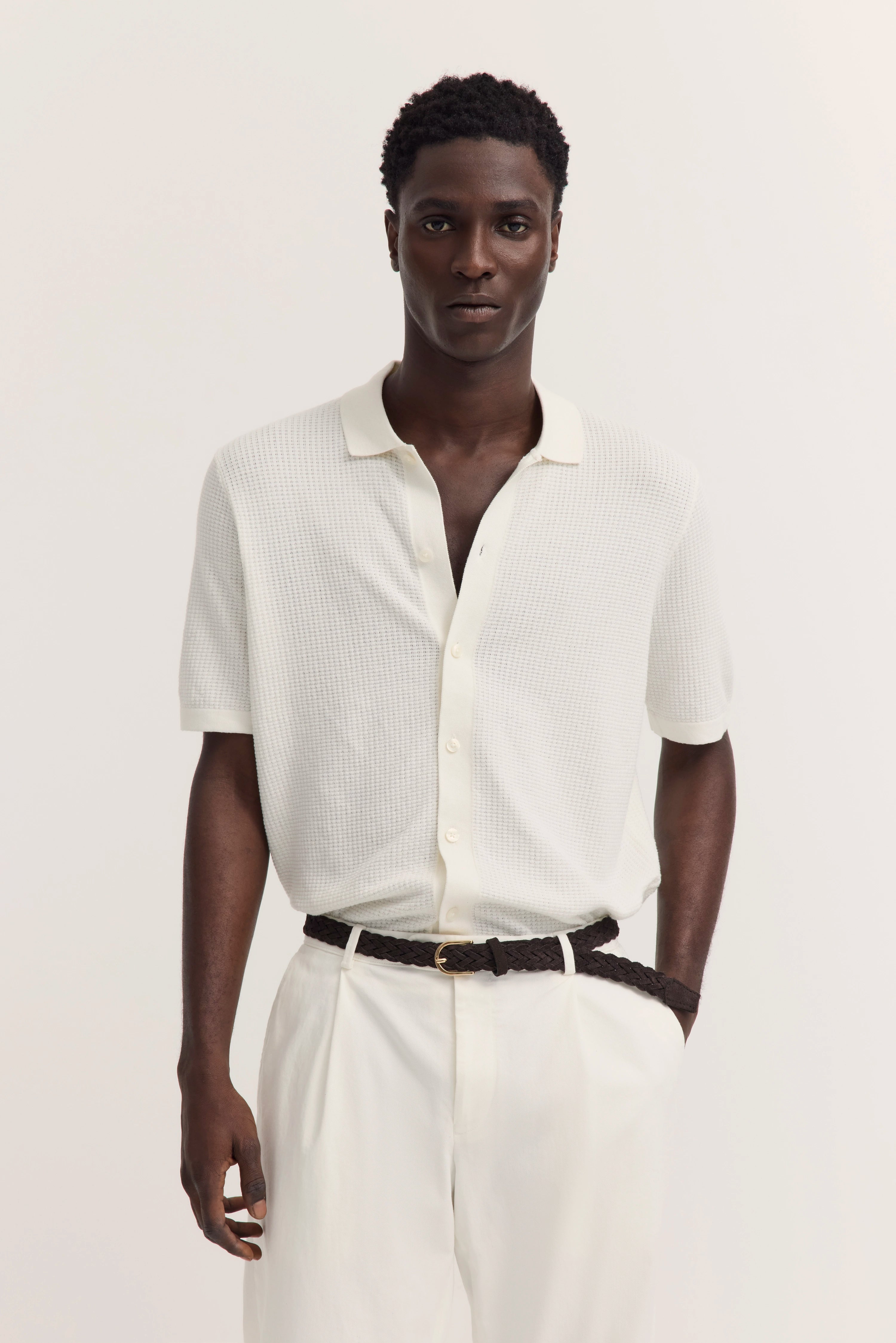 Weiße bugatti Polo-Shirt und Hose, Model stehend mit Händen in den Taschen, legerer Look.