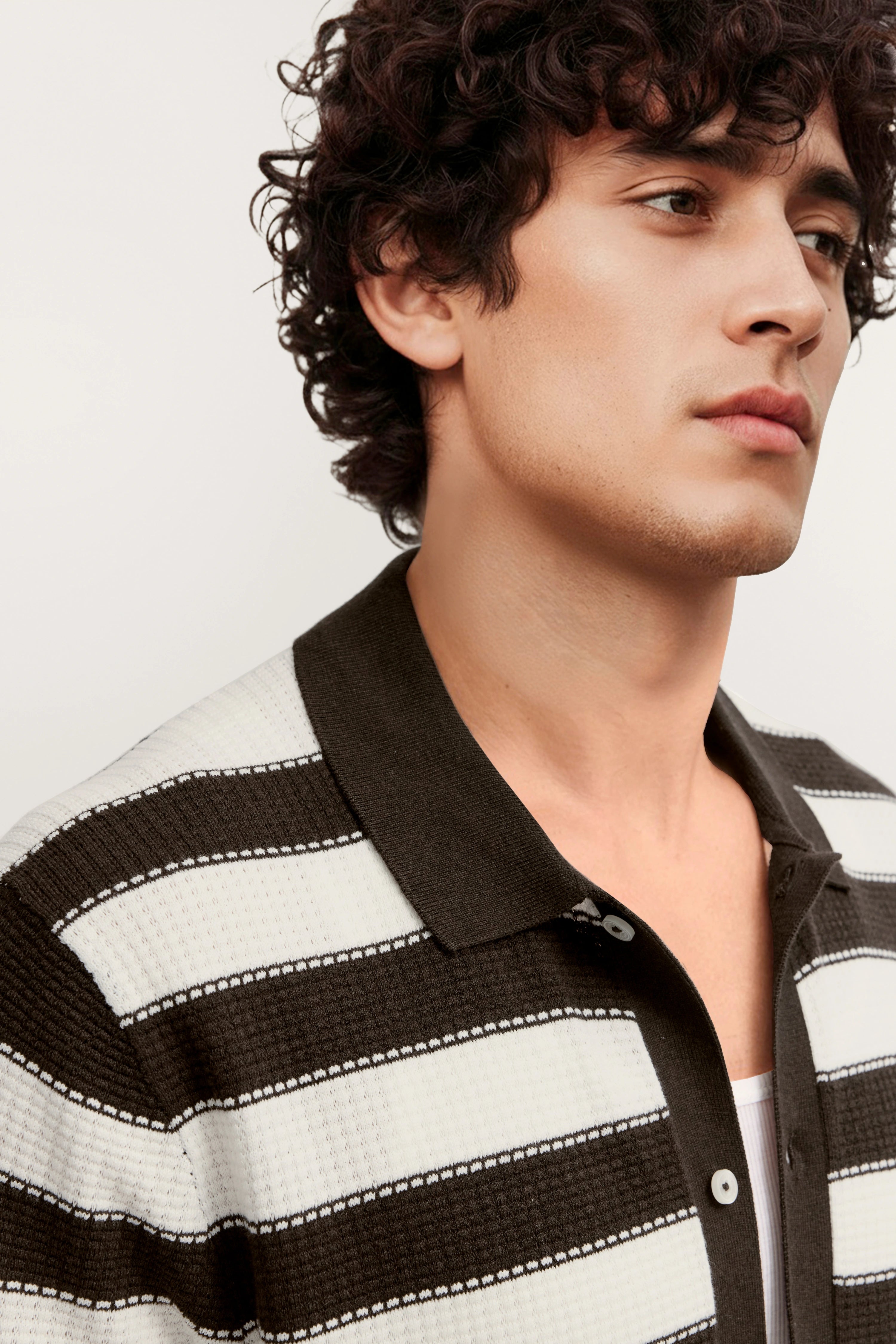 "Model in gestreiftem bugatti Polo, schwarz-weiß, legeres Posing, naher Blickwinkel."