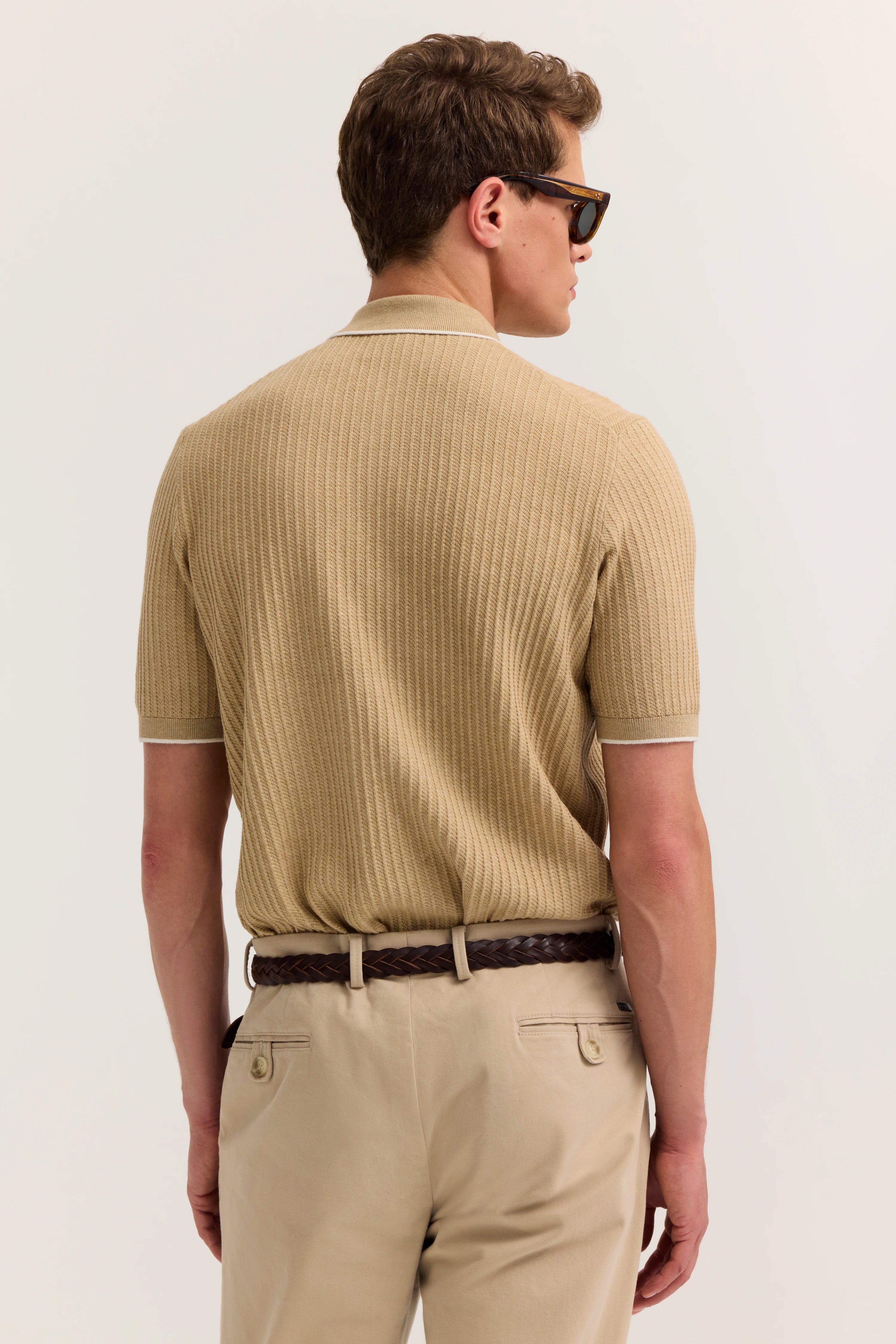 Beige Polohemd und Chino in Rückansicht, legeres Modelbild, entspannte Pose.