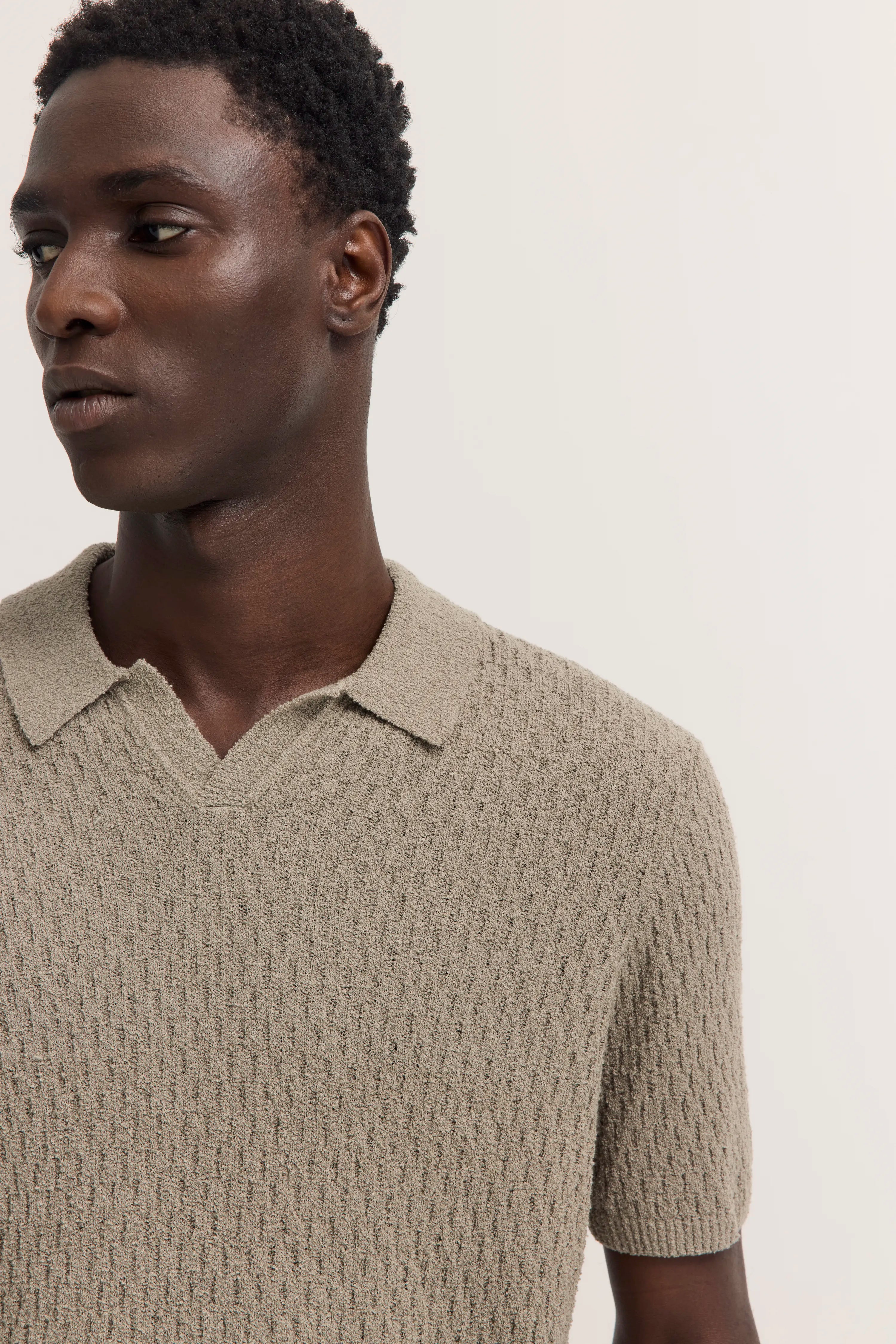 Model in beigefarbenem Strickpolo von bugatti, legeres Posing, Halbprofil.