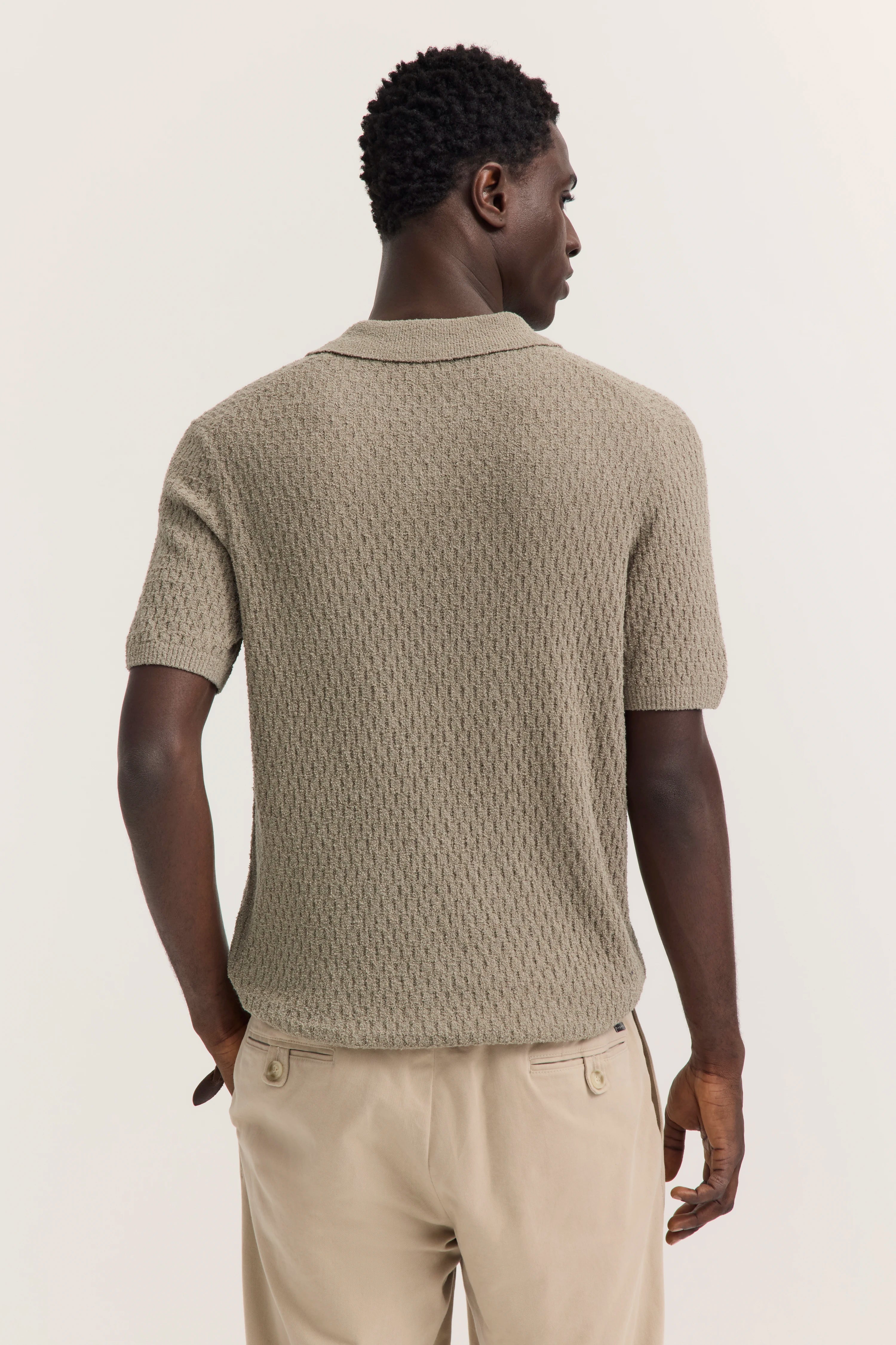 Beiges Strickpolo und beige Chinos im legeren Modelbild von hinten.