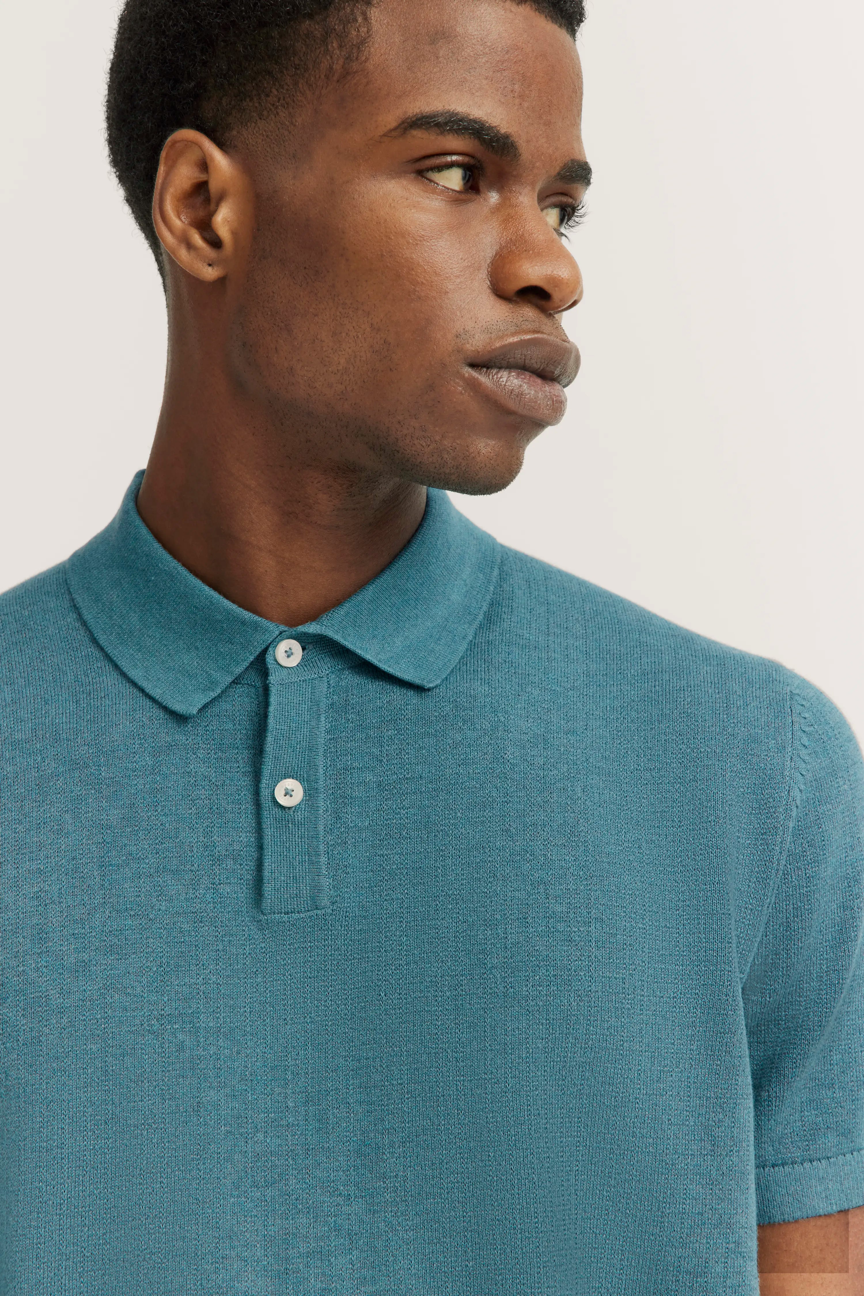 Close-up of blue polo shirt, model turned sideways.