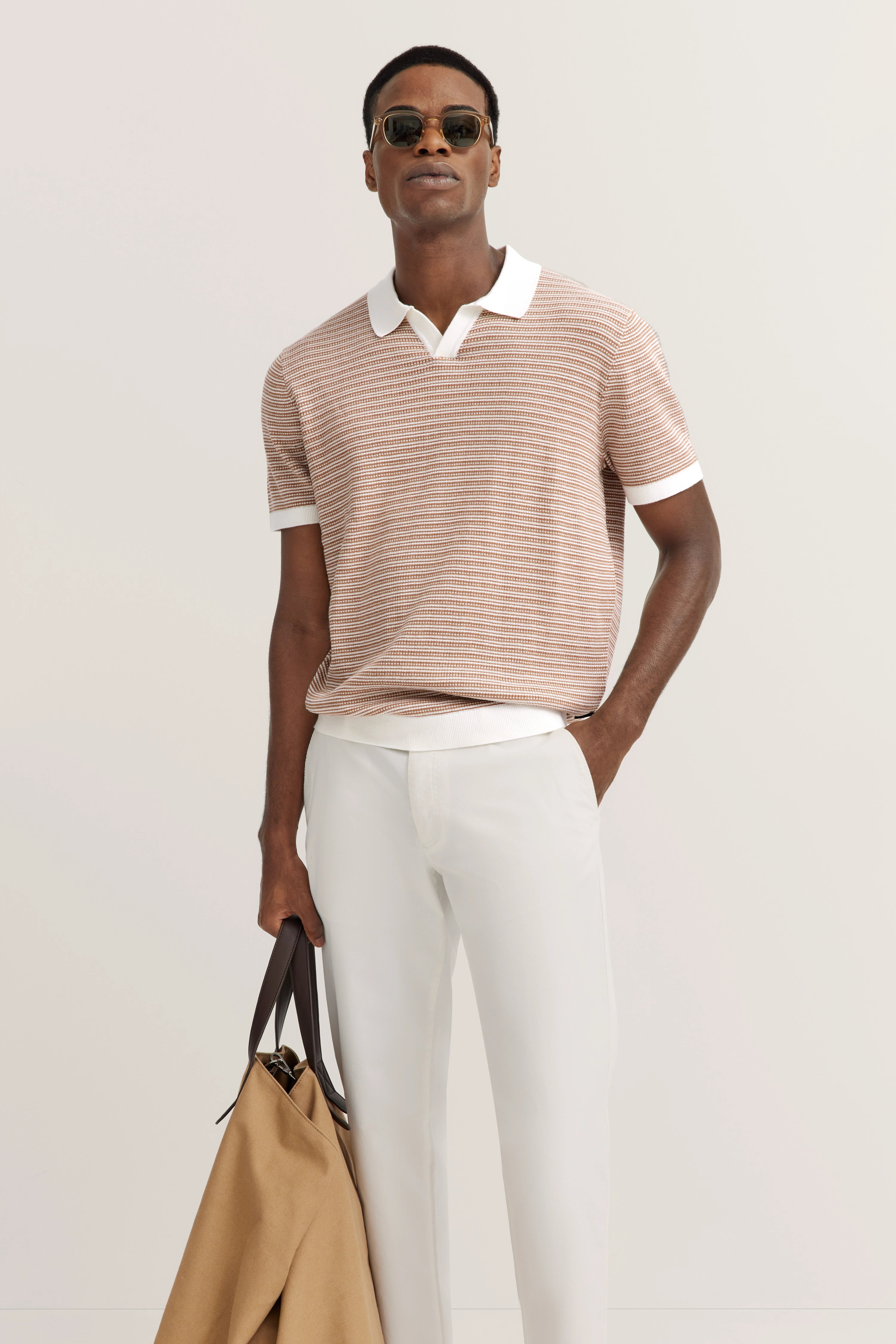 bugatti model image: Man in striped polo, white pants, sunglasses, relaxed pose.