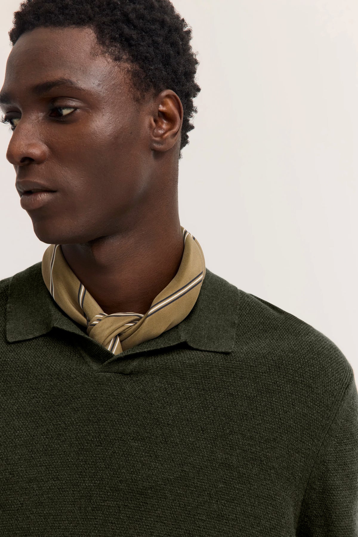 Modelbild: Olivgrüner Pullover, beigefarbener Schal, lässiges Posing.