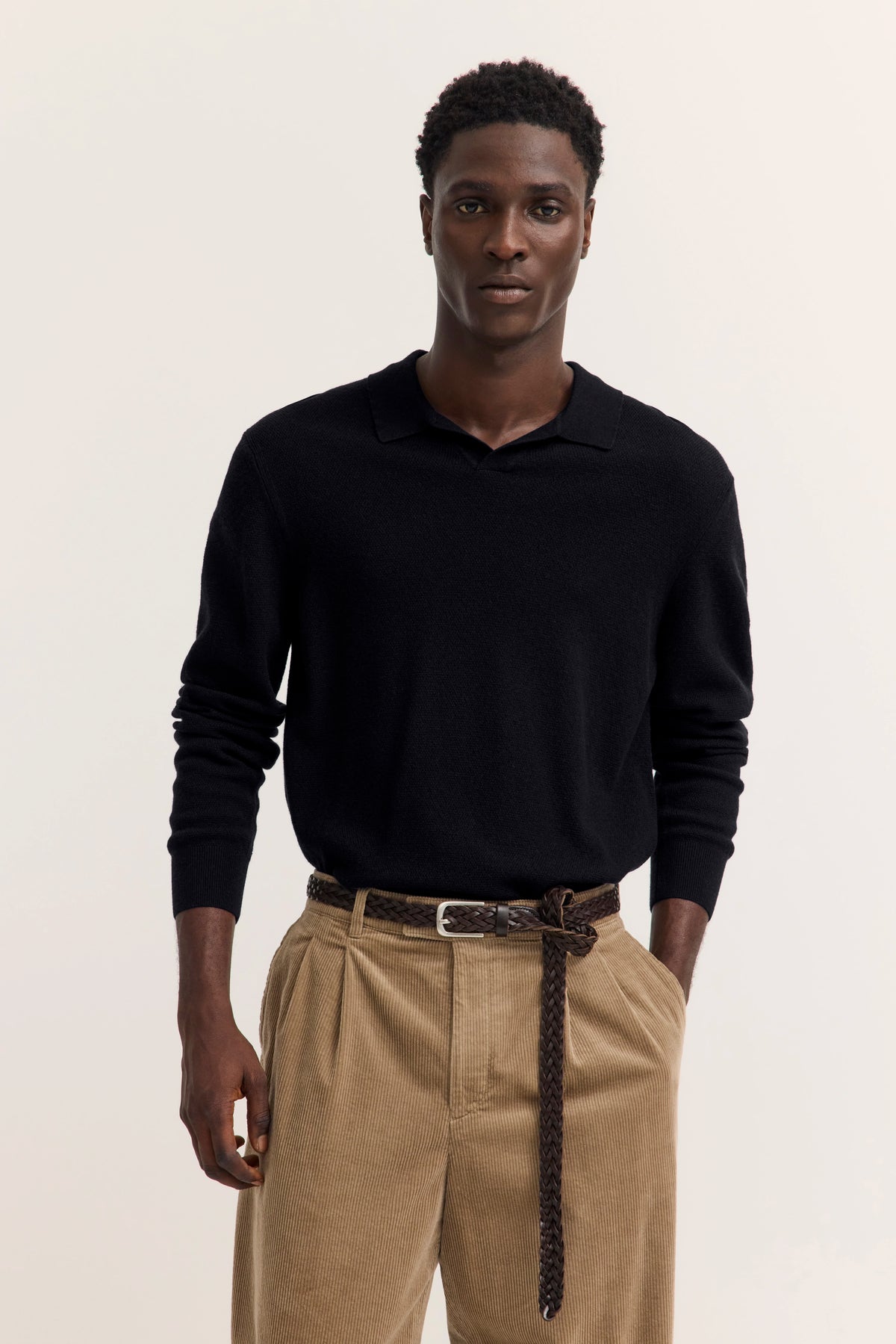 Schwarzer bugatti Pullover, beige Hose, Modelbild mit entspanntem Posing, zeitloser Stil.