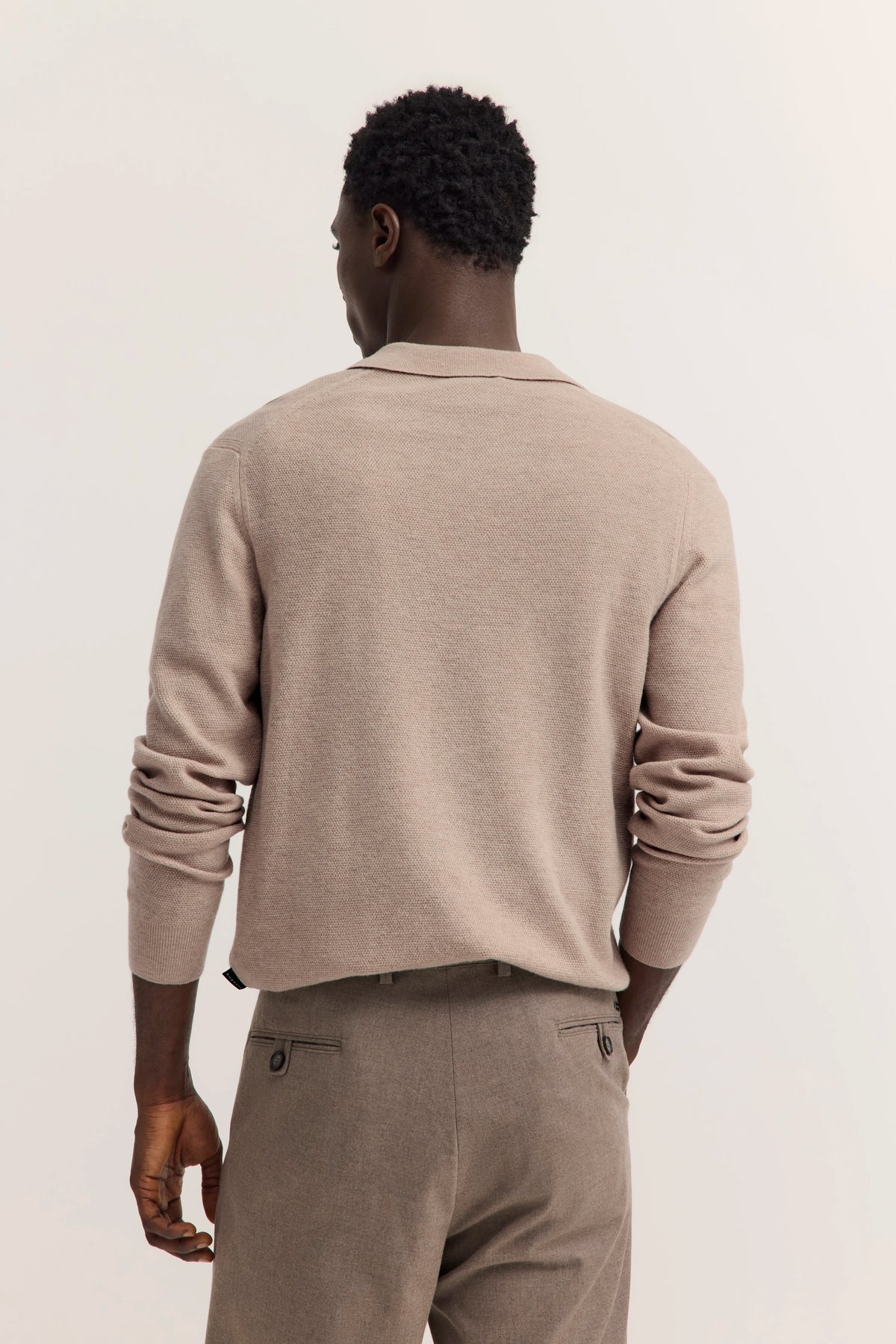 Rückansicht Modelbild mit beige bugatti Pullover und Hose, entspannte Pose.