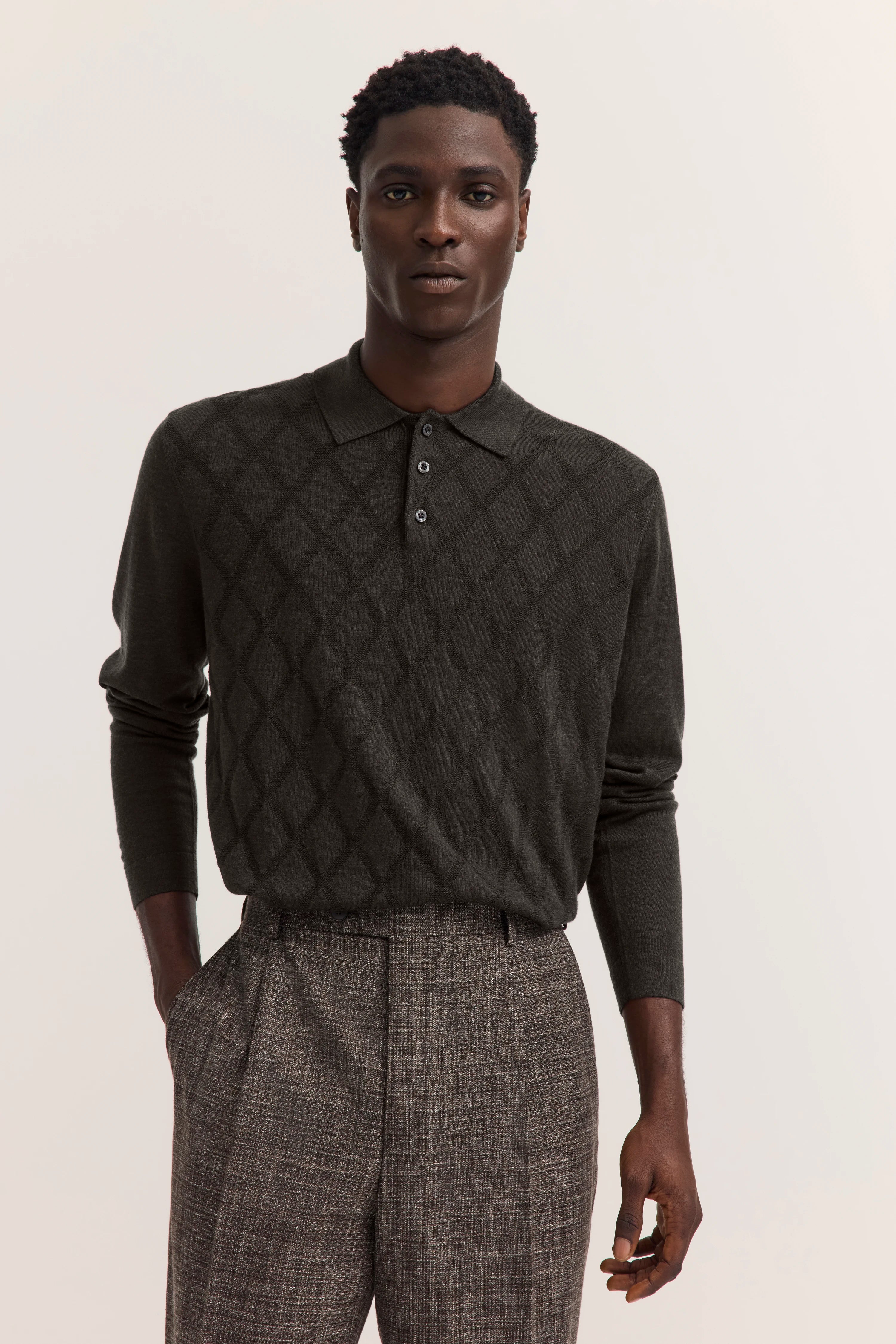 Model trägt grauen Pullover mit Argyle-Muster und graue karierte Hose von bugatti.