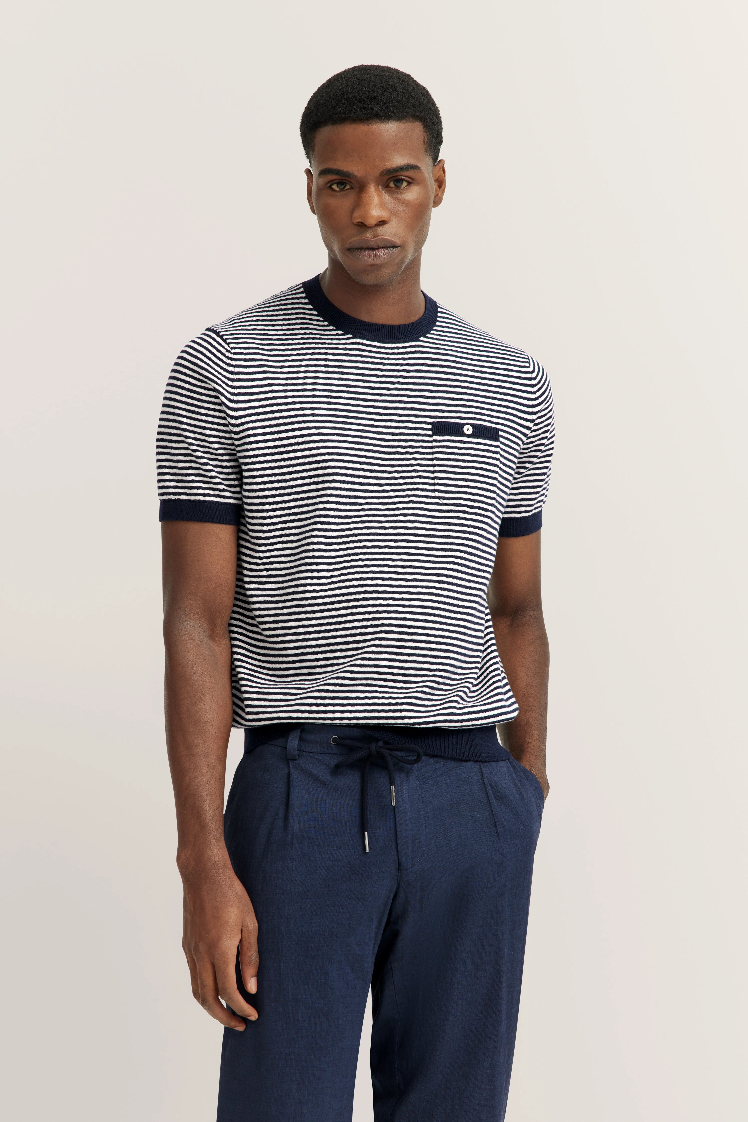 Striped navy-white shirt, blue trousers, relaxed model pose, bugatti style.