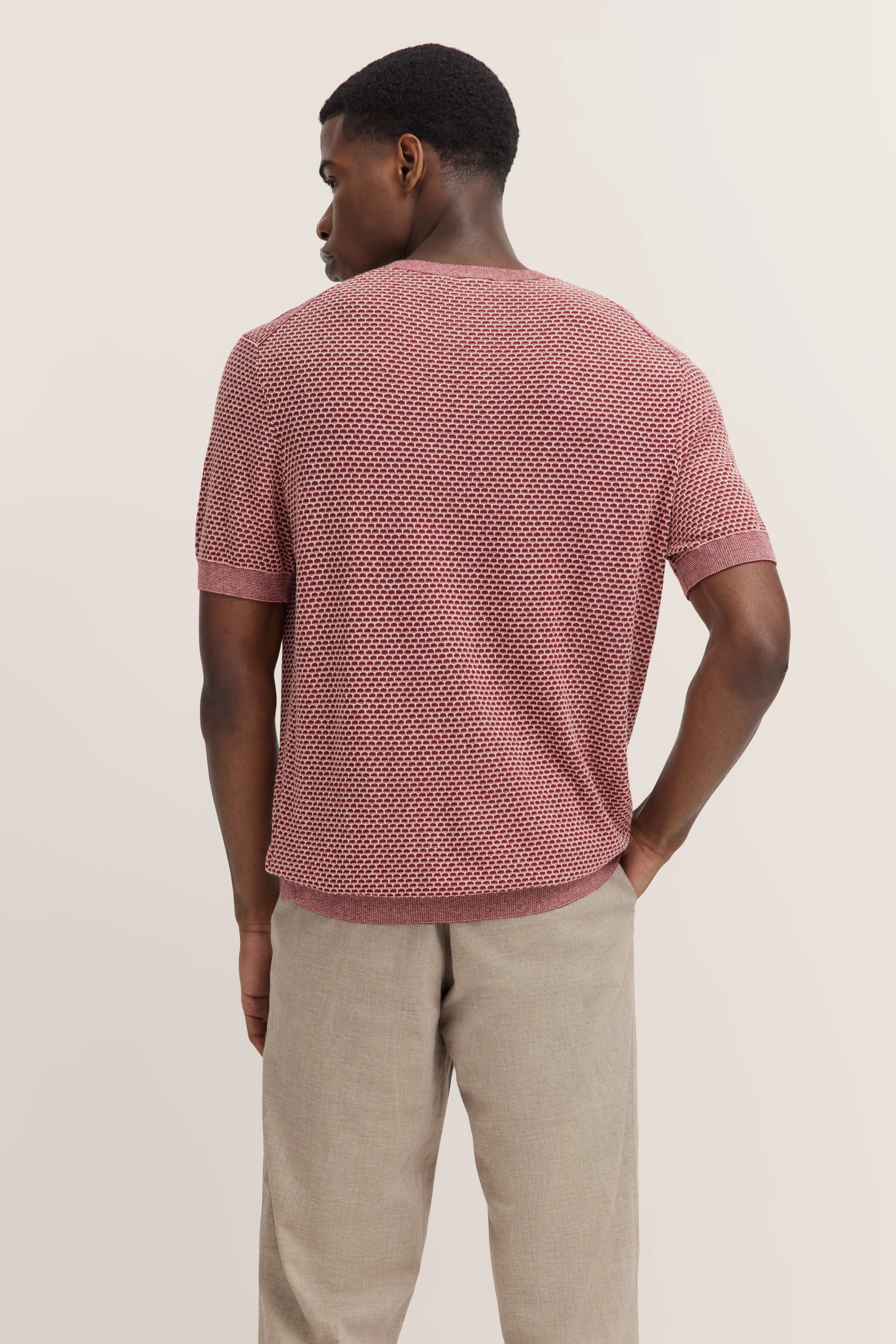 Achteraanzicht model in rood bugatti shirt met patroon, beige broek, relaxte houding.