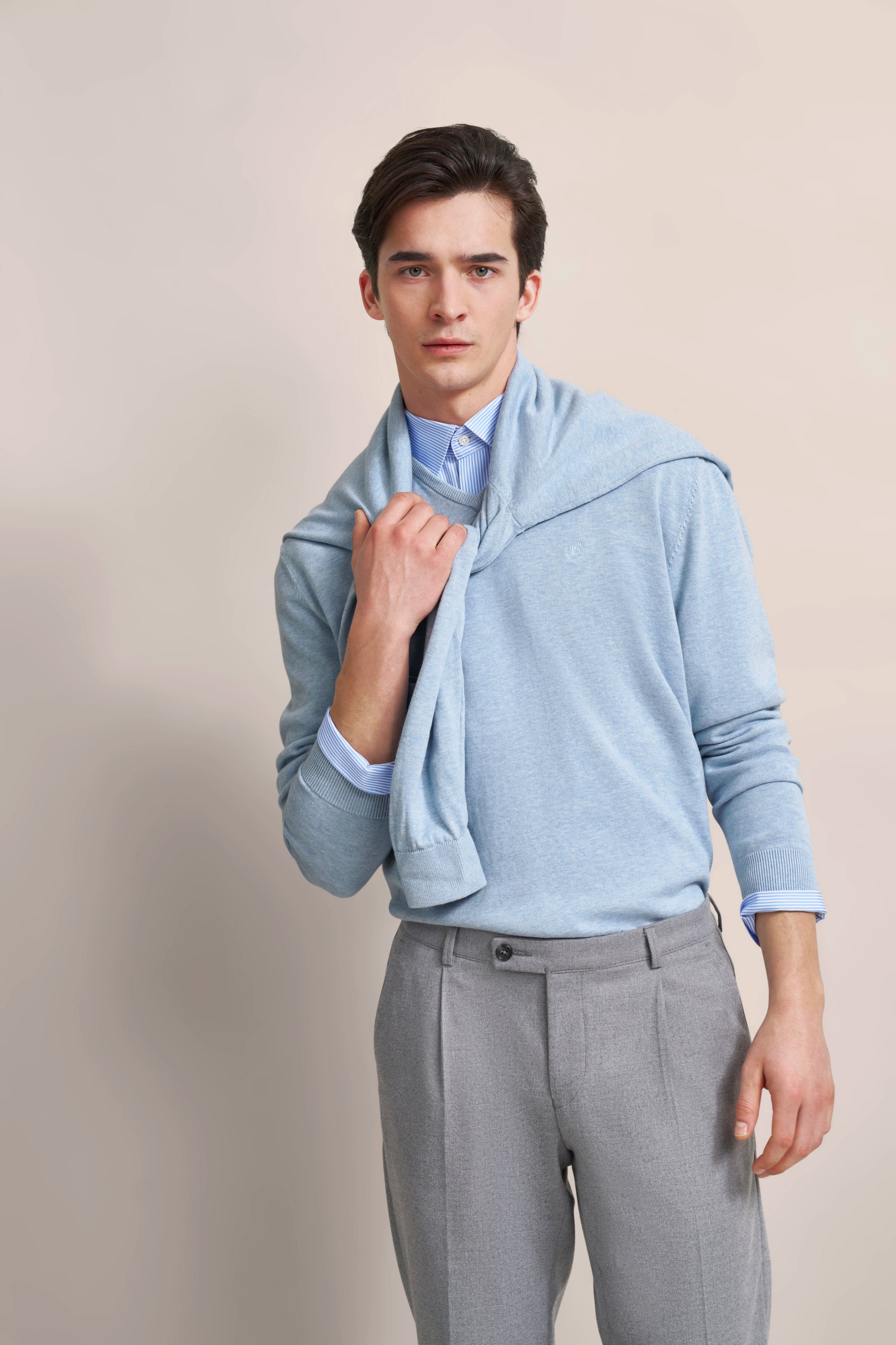 Modell in hellblauem Pullover und grauer Hose, legeres Posing, stilvoller Look von bugatti.