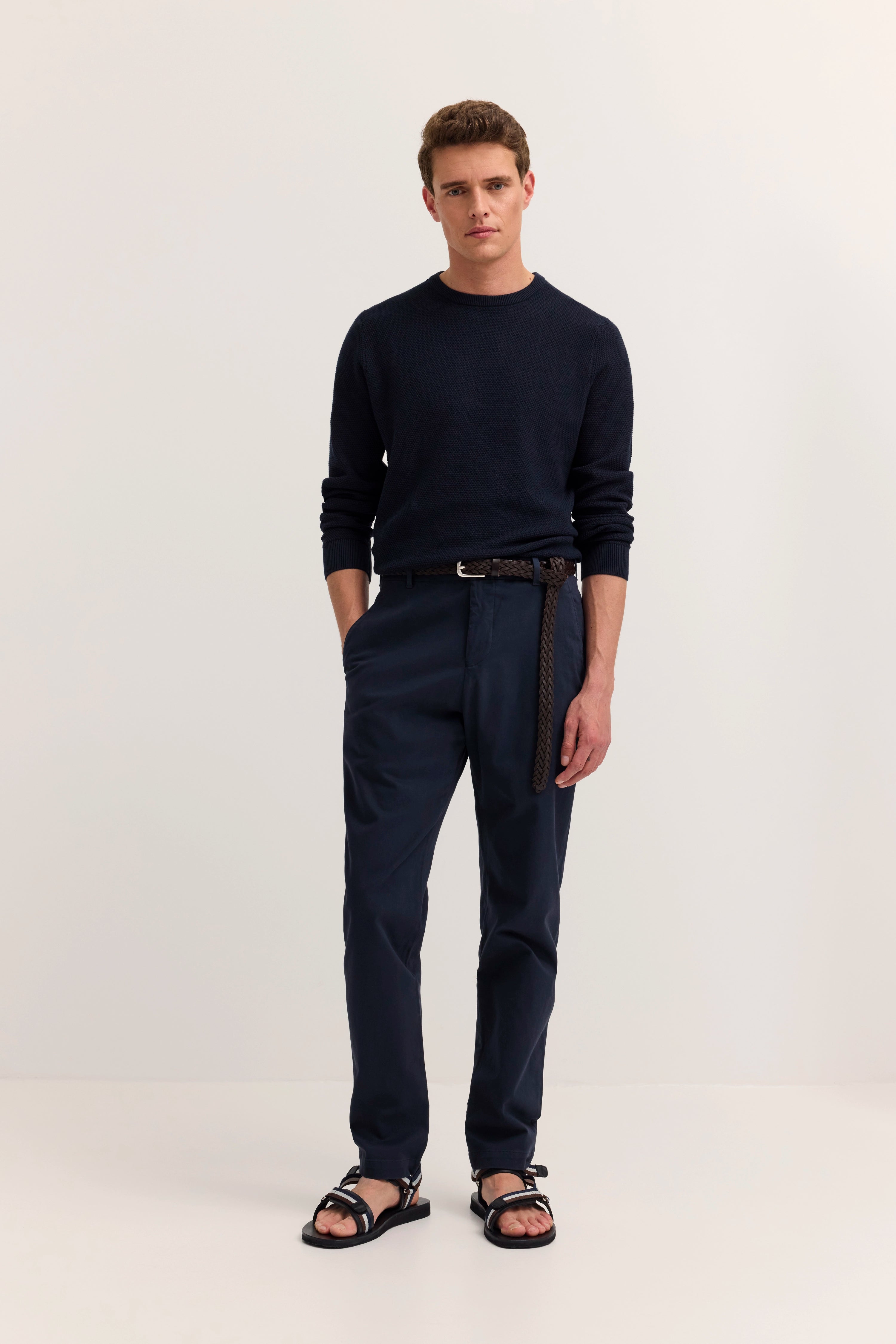 Model in navy bugatti Pullover und Chinos, lässig stehend, schwarze Sandalen.