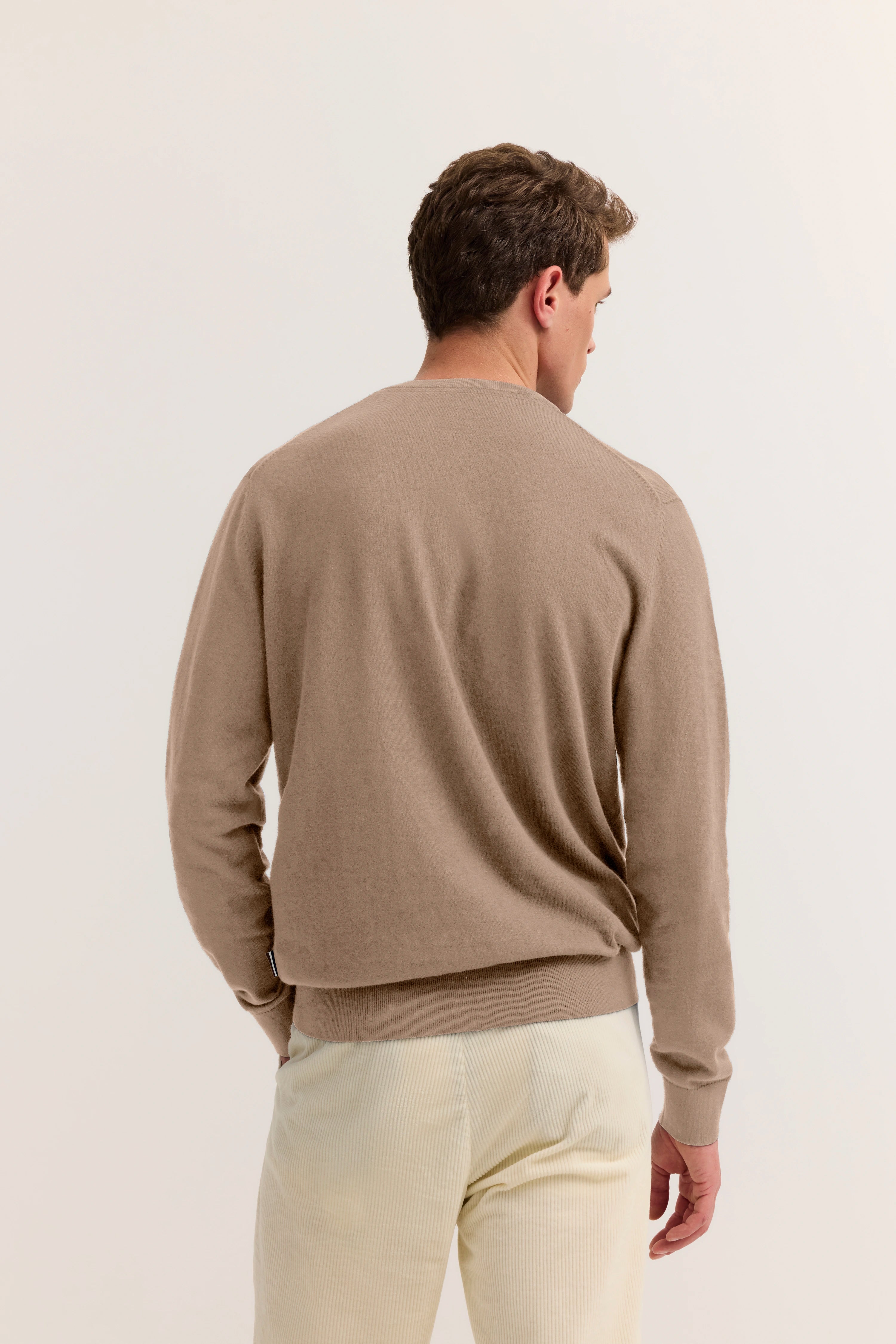 Beiges bugatti Pullover-Modelbild, Rückansicht, lässige Pose, cremefarbene Hose.