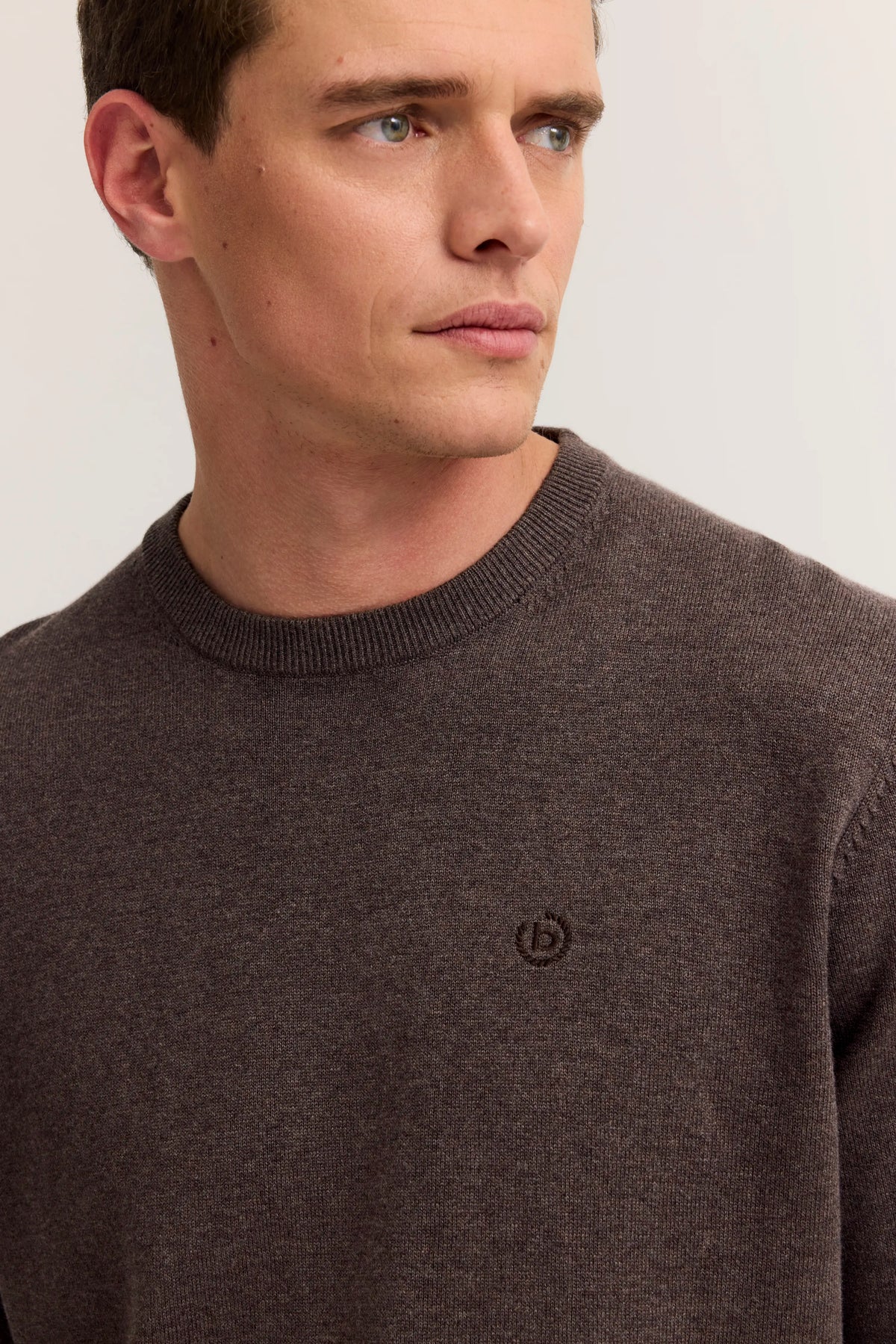 Brauner bugatti Pullover, graue Hose, Model von hinten, lässige Pose.