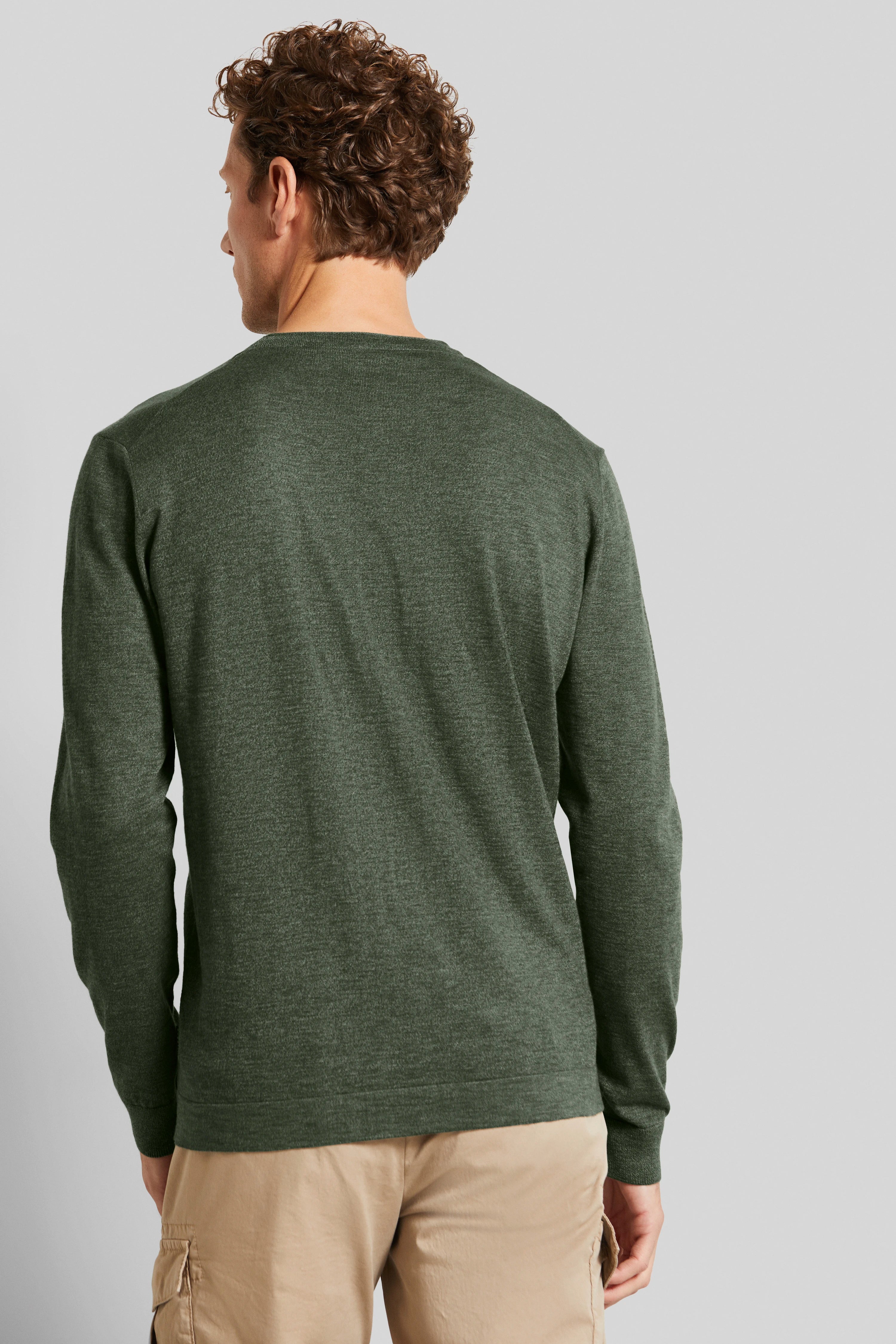 Grünes Langarmshirt, legeres Modelbild von hinten, beige Hose.