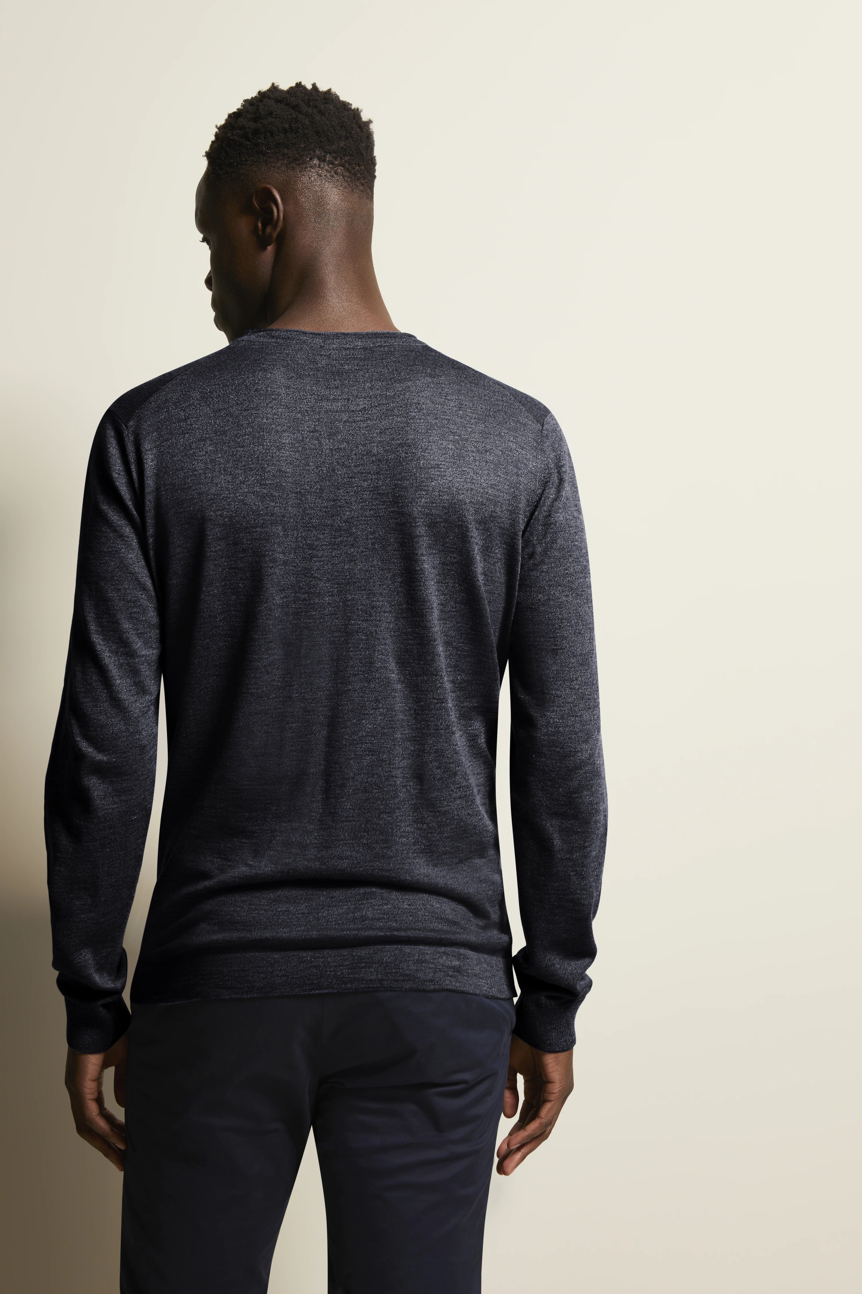 bugatti Modelbild: Mann in dunkelgrauem Pullover und Hose, Rückansicht, lässige Pose.