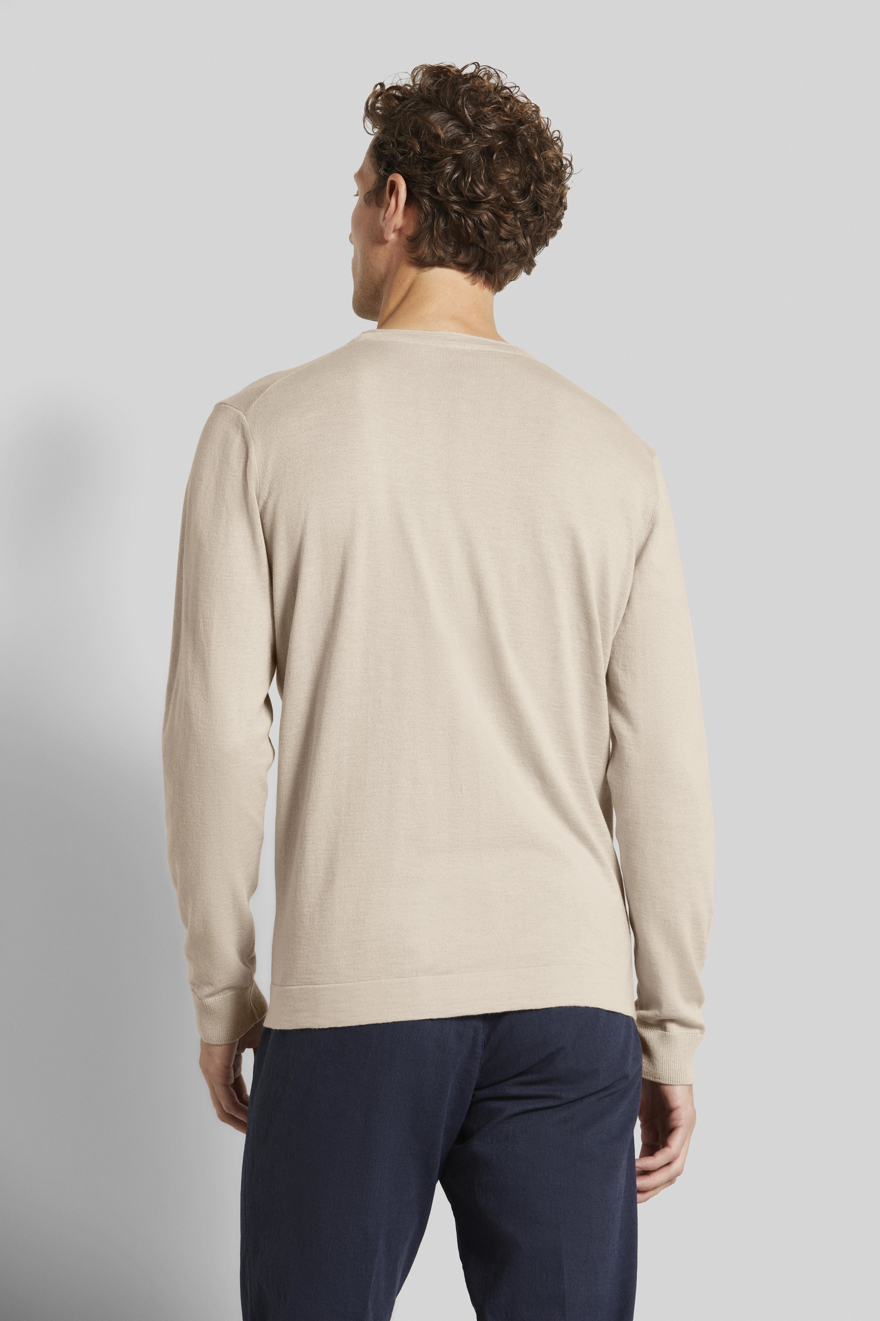 Beiges bugatti Langarmshirt, Rückansicht, kombiniert mit dunkelblauer Hose, legeres Modelbild.