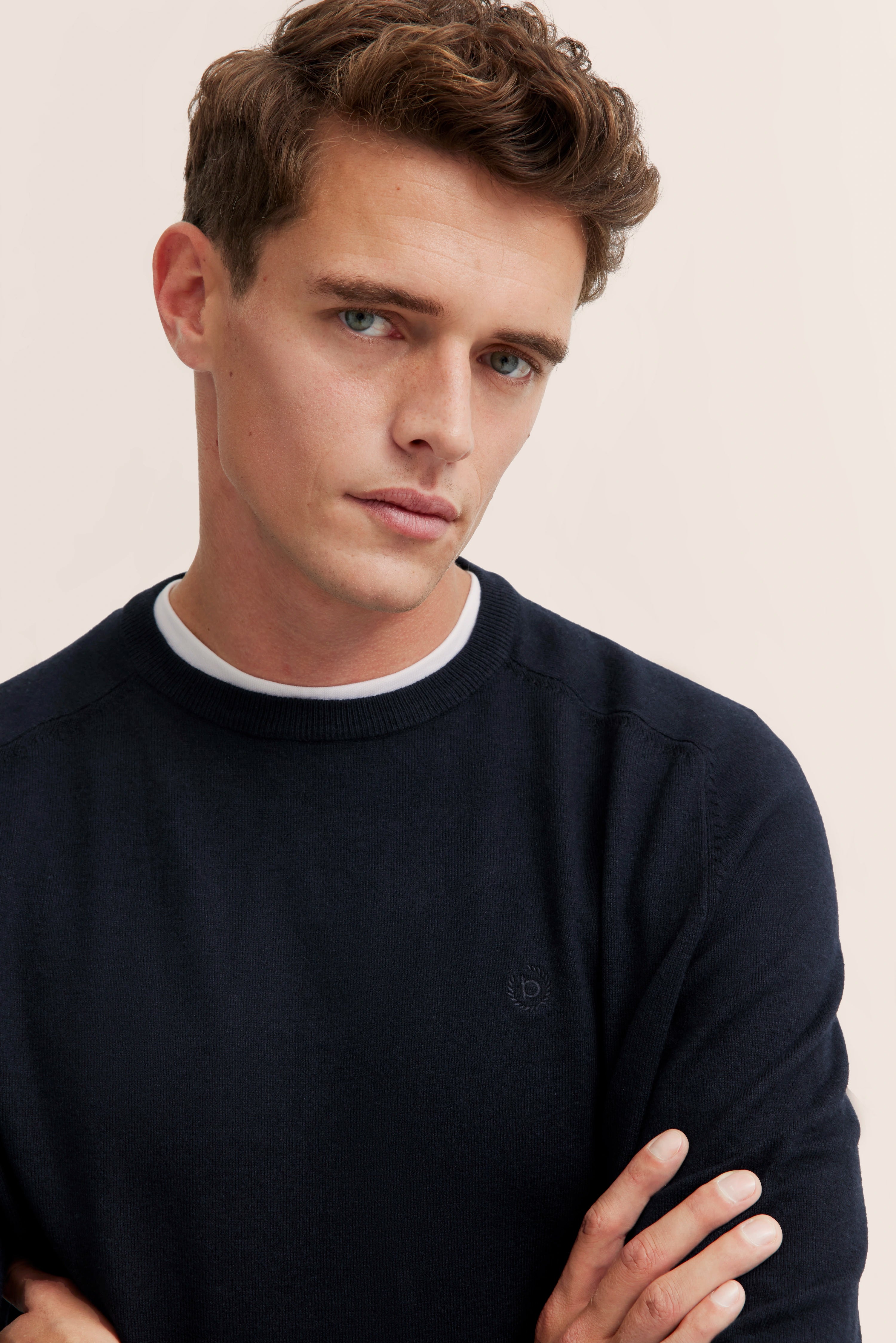 Bust of a man in a dark blue bugatti sweater with white shirt detail.