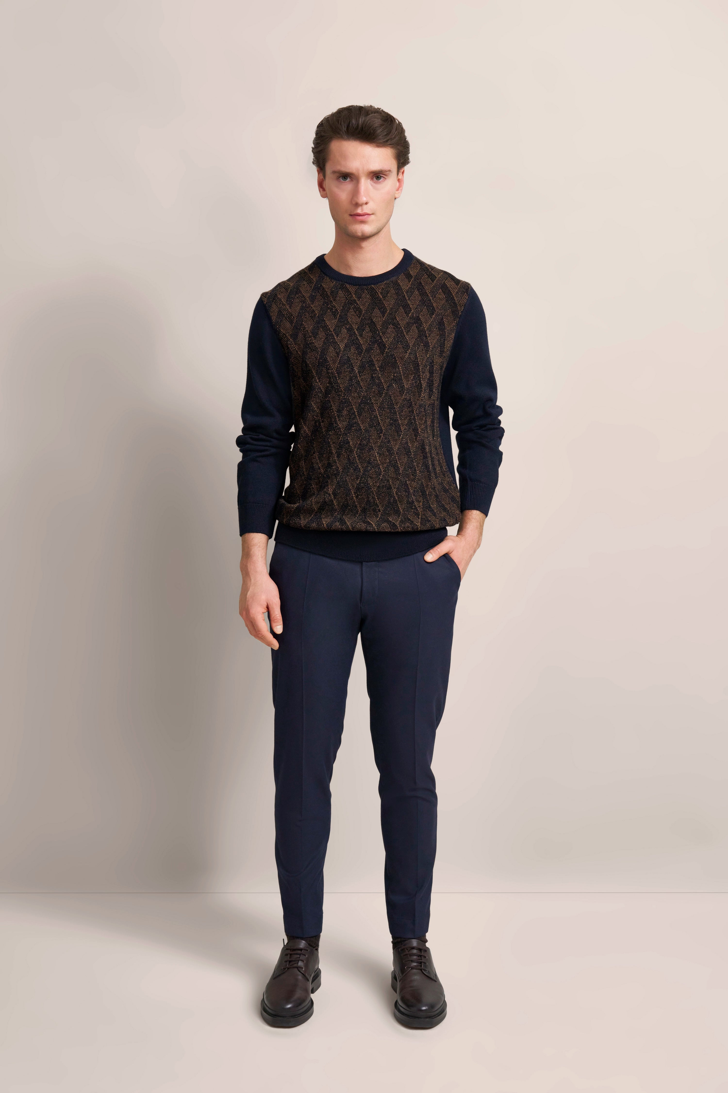 bugatti Modelbild: Mann in braunem gemustertem Pullover, dunkelblauer Hose, schwarze Schuhe, lässiger Stand.